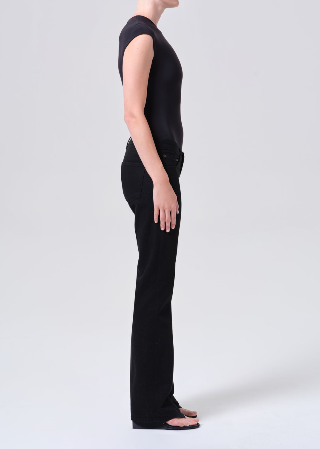 Person wearing a black sleeveless top and pants on a white background