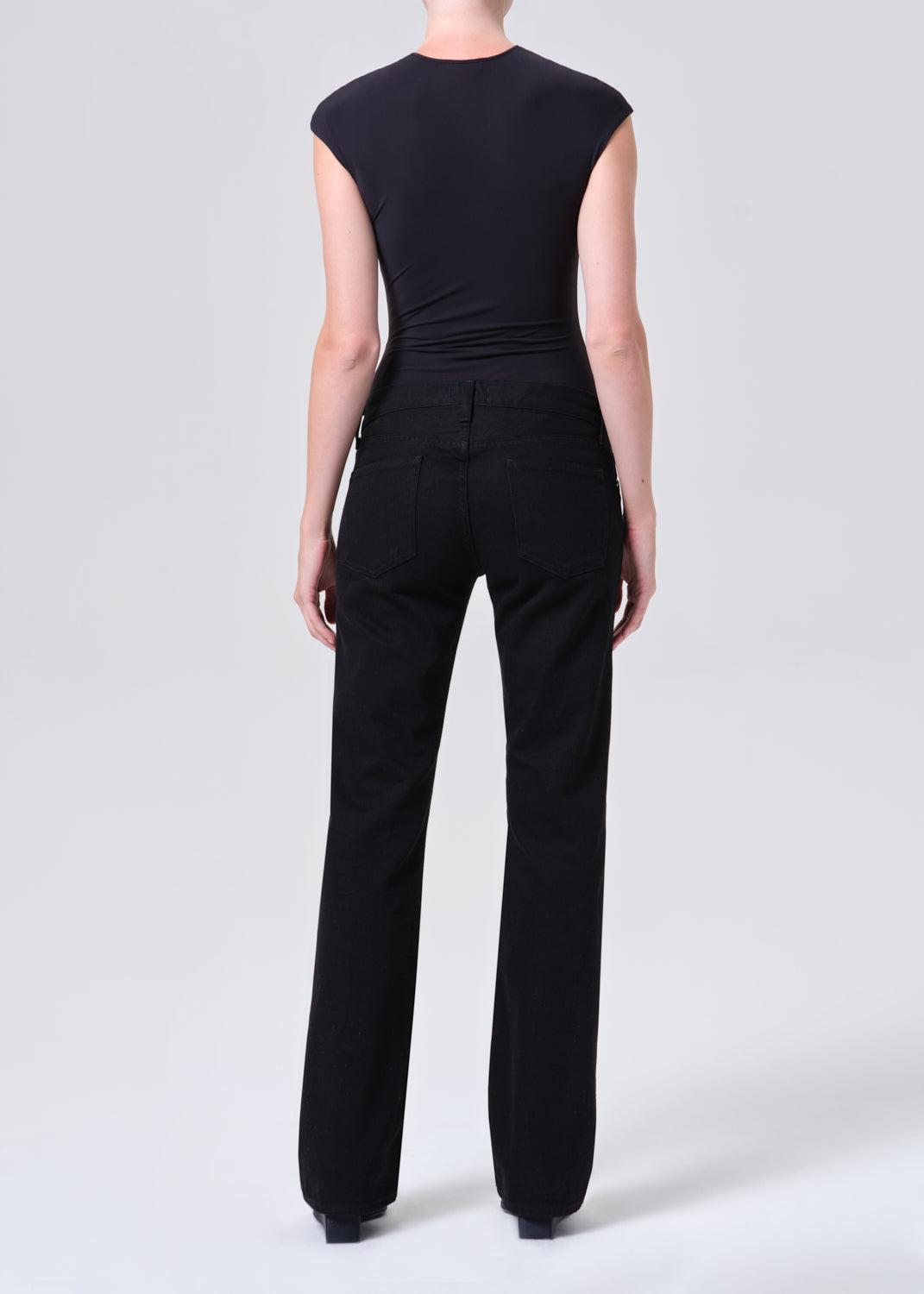 Person wearing a black sleeveless top and pants on a white background