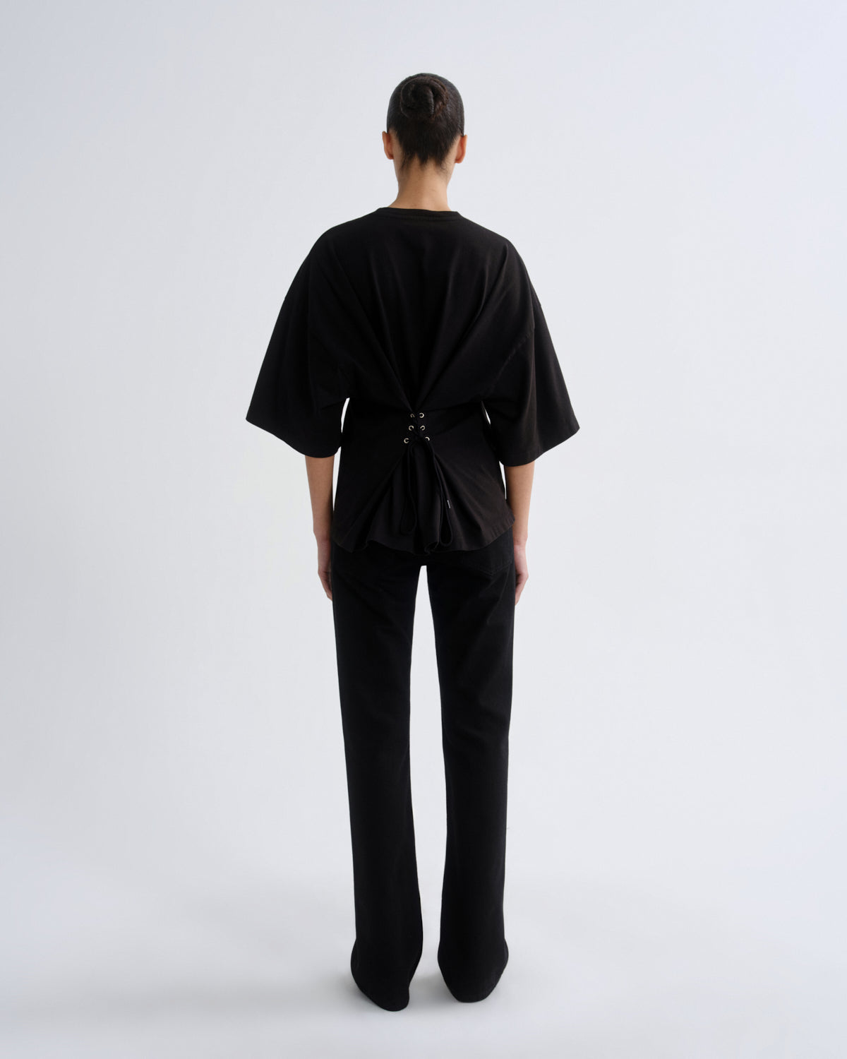 Person wearing a black outfit with a draped design on a white background