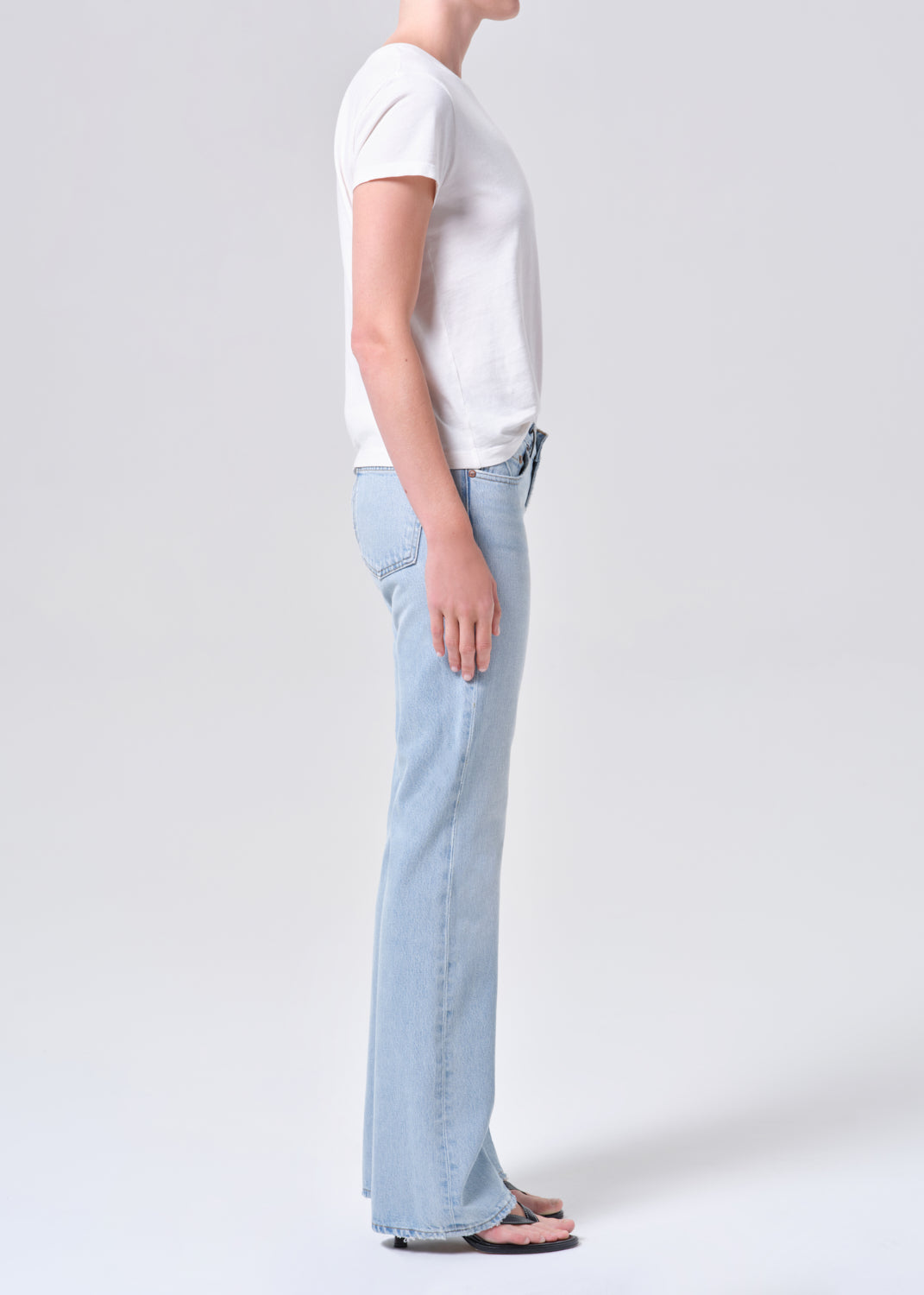 Person wearing light blue jeans and a white t-shirt on a plain background