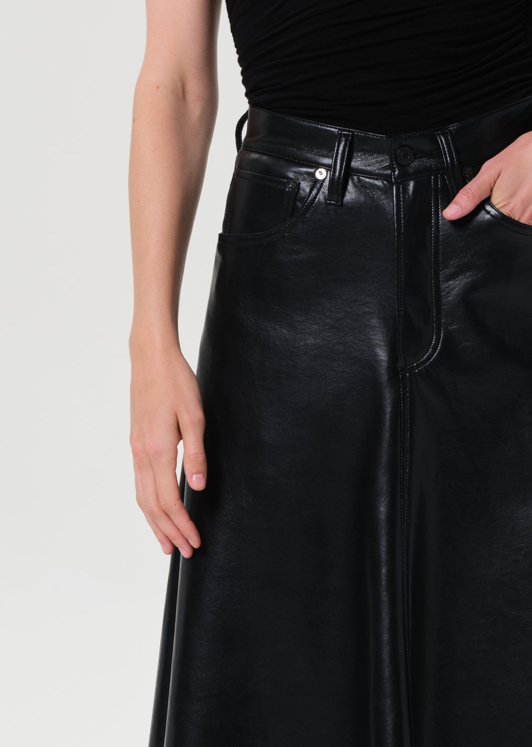 Black leather skirt worn by a person on a light gray background