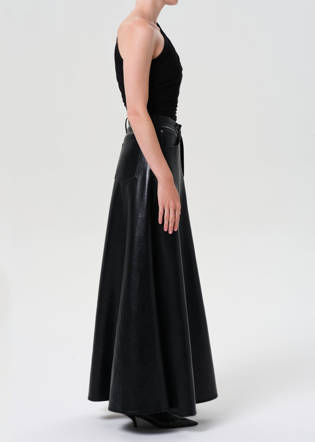 Person wearing a long black leather skirt on a white background