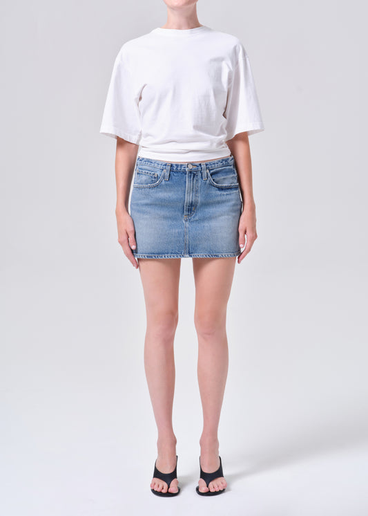 Person wearing a white t-shirt and denim skirt on a plain background