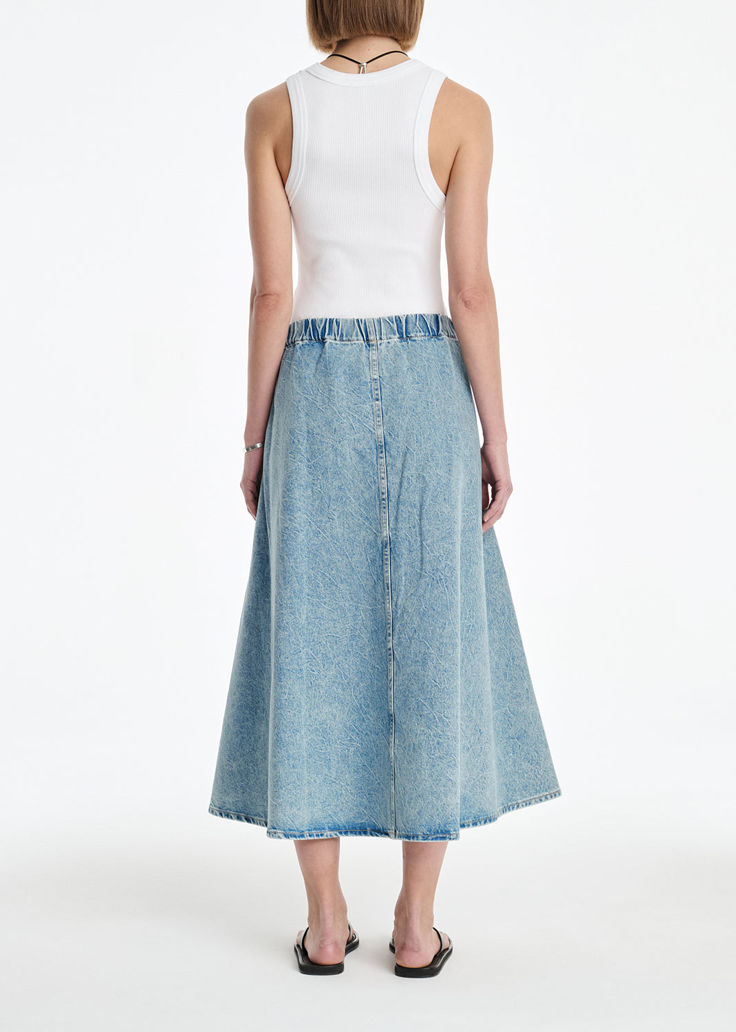 Woman wearing a white top and denim skirt on a white background