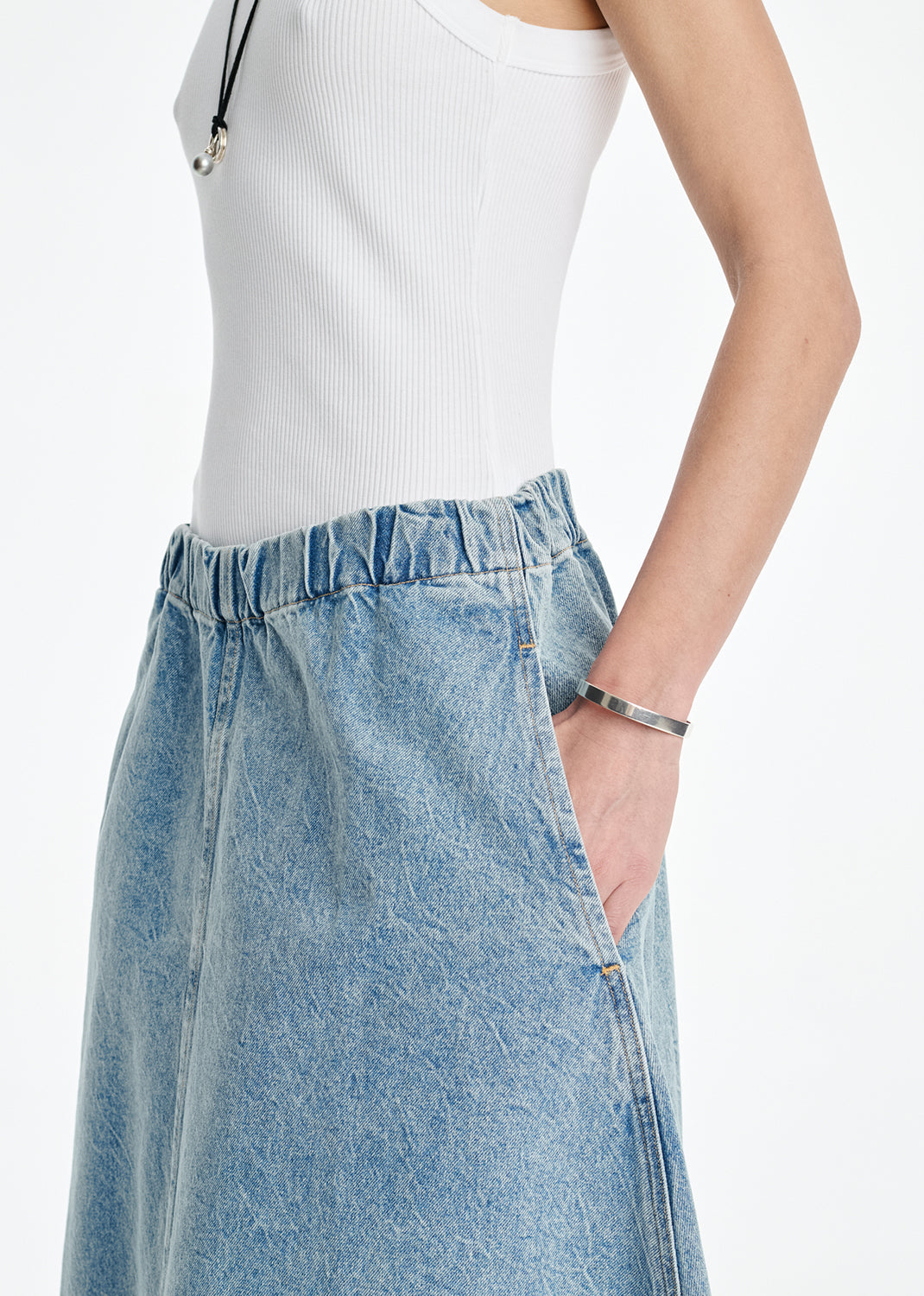 Person wearing a white top and blue denim skirt on a white background