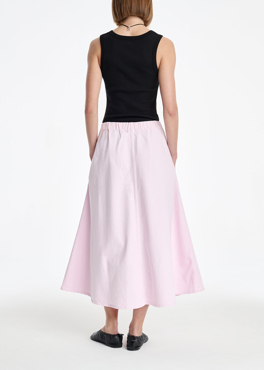 Person wearing a black top and pink skirt on a white background