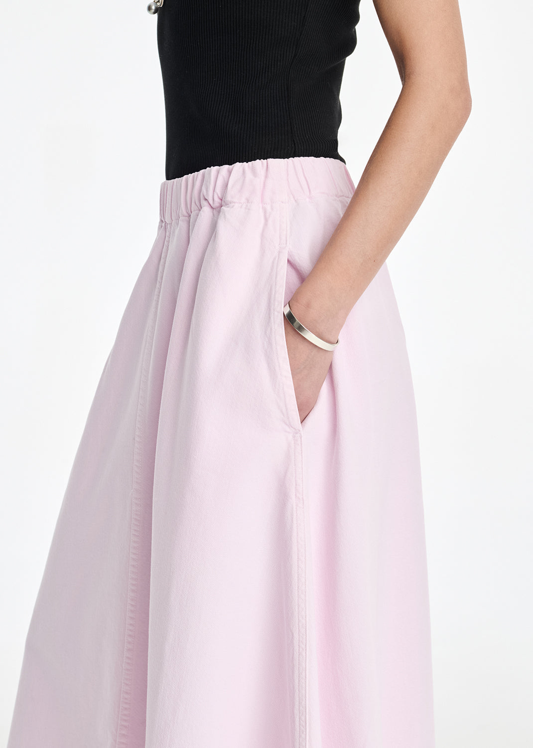 Person wearing a black top and light pink skirt on a white background