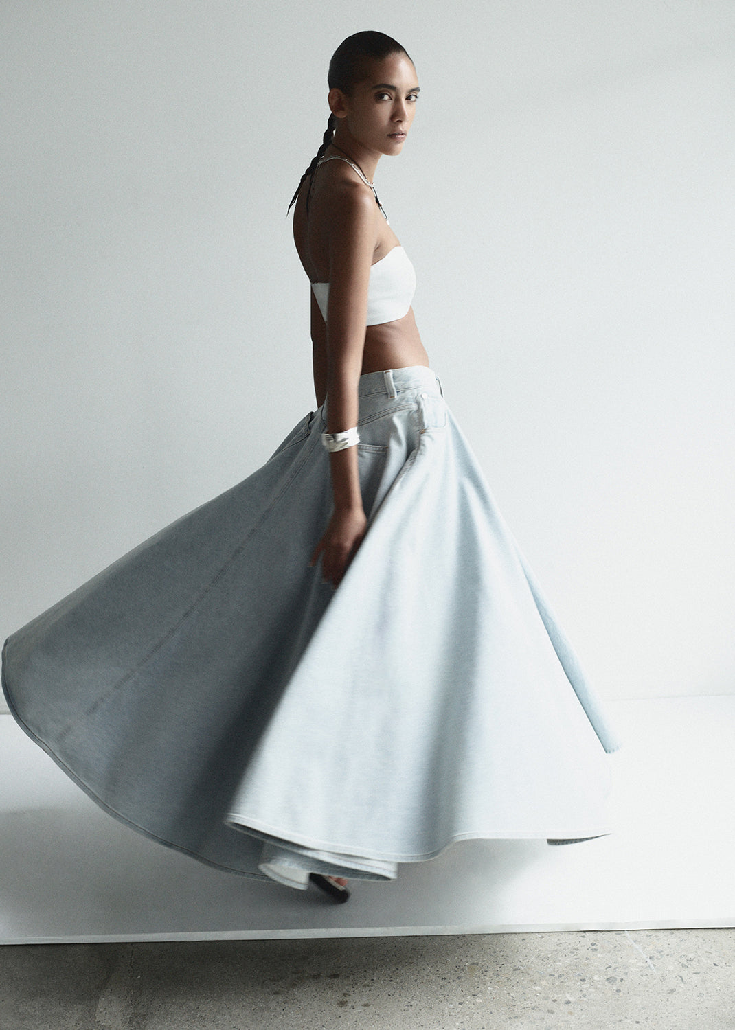 Woman wearing a white top and light blue skirt on a plain background