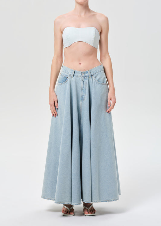 Woman wearing a strapless top and light blue denim skirt on a white background