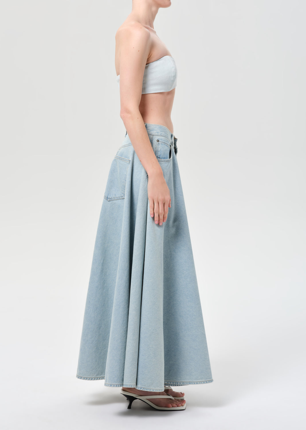 Person wearing light blue denim pants on a white background