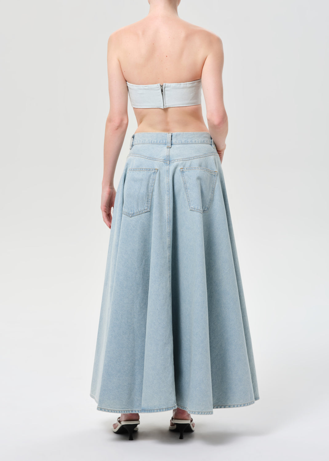Person wearing a light blue strapless top and long skirt on a white background