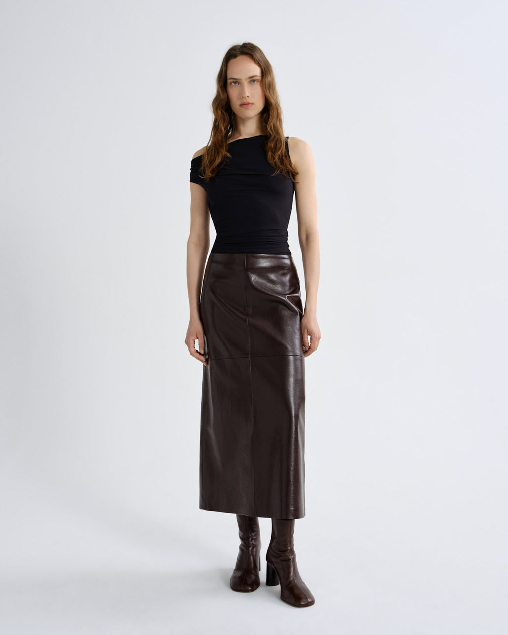 Woman wearing a black top and brown leather skirt on a grey background