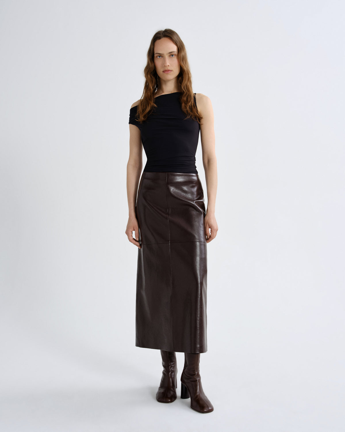 Woman wearing a black top and brown leather skirt on a grey background