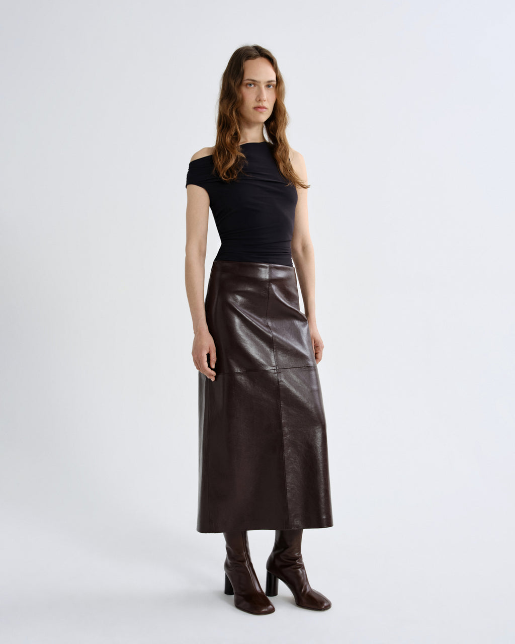 Woman wearing a black top and brown leather skirt on a grey background