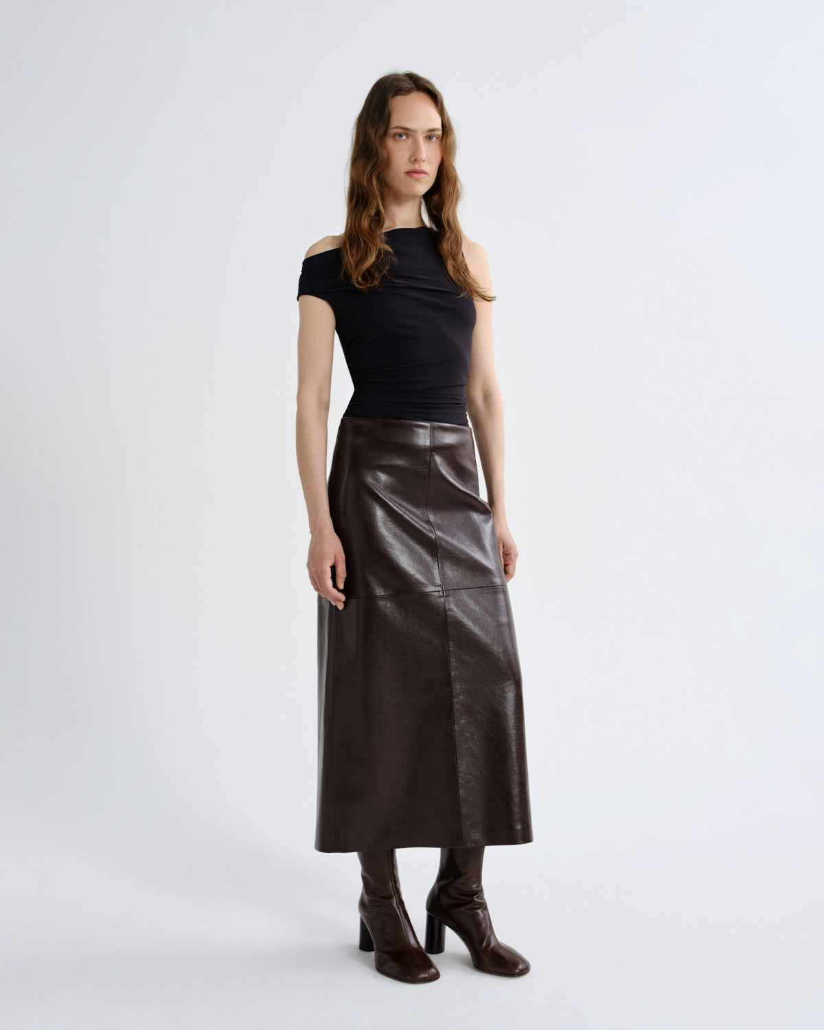 Woman wearing a black top and brown leather skirt on a grey background