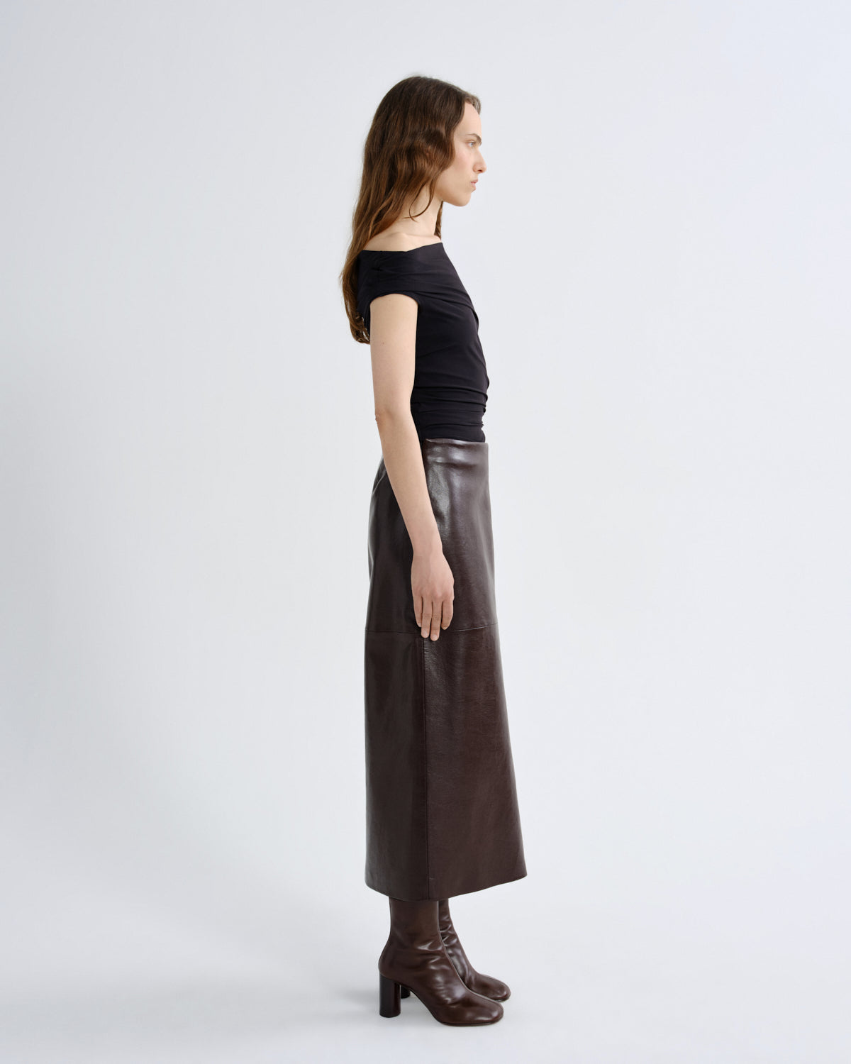 Woman wearing a black top and brown leather skirt on a grey background