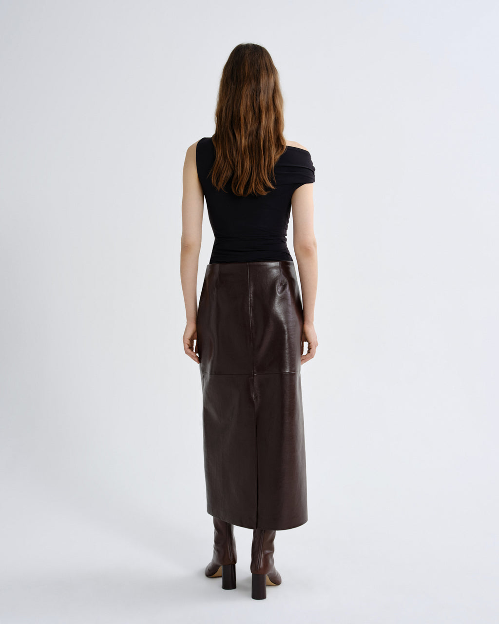 Woman wearing a black top and brown leather skirt on a grey background