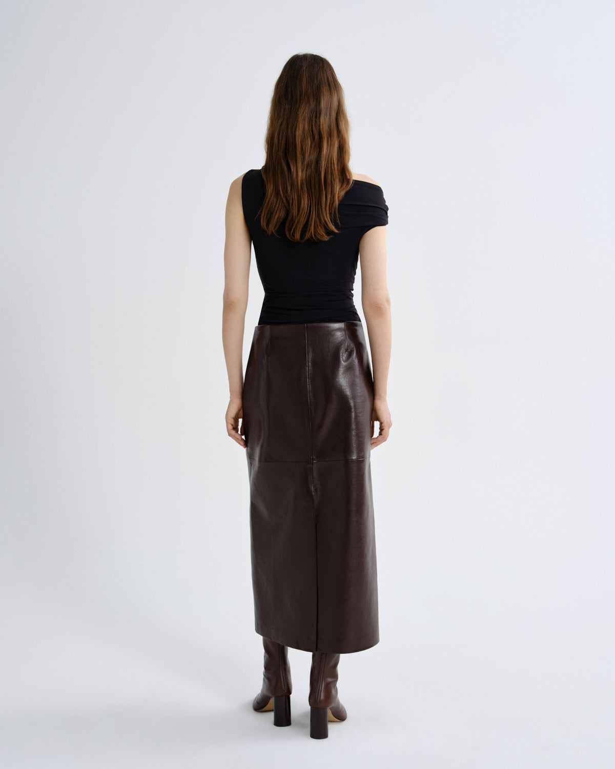 Woman wearing a black top and brown leather skirt on a grey background