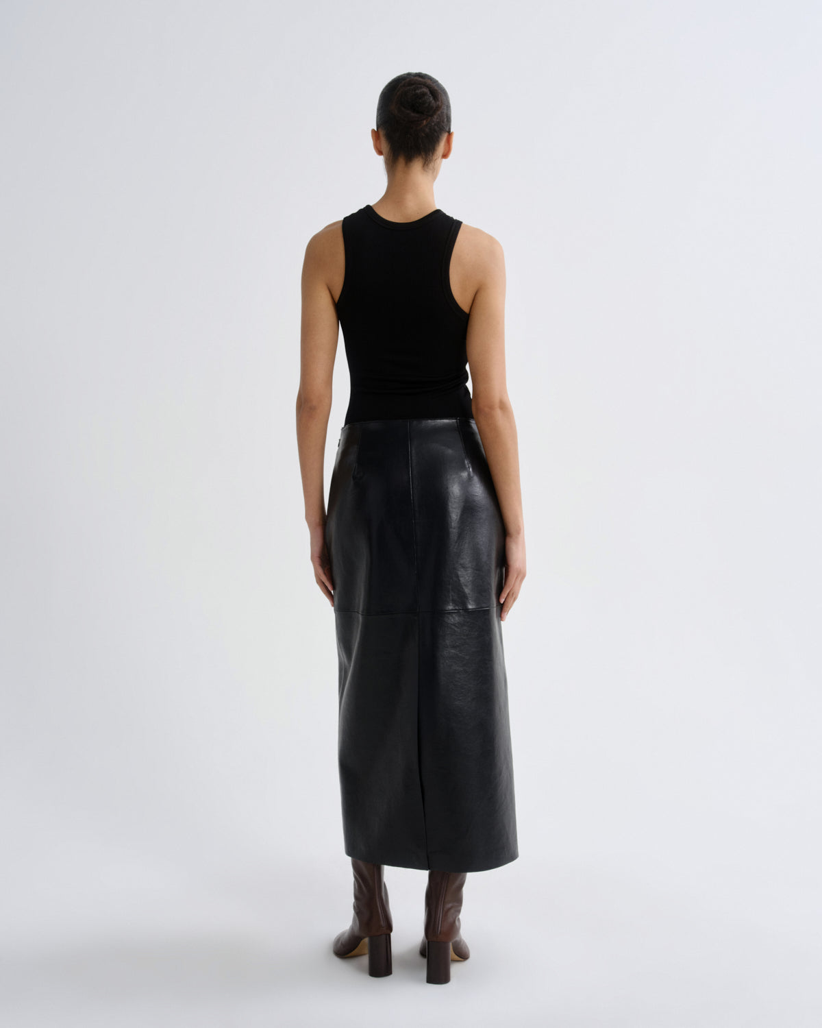 Person wearing a black leather skirt and black top on a white background