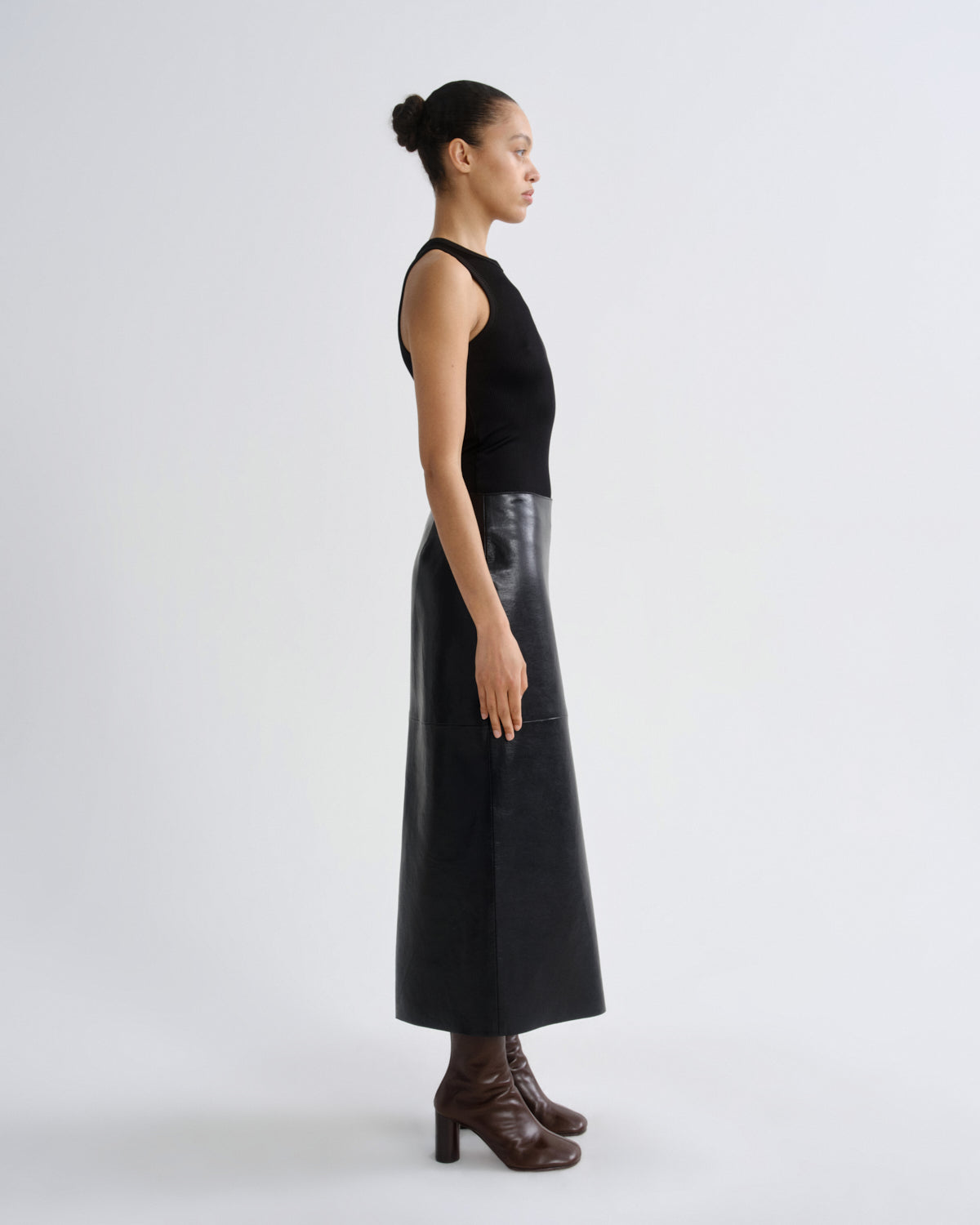 Woman wearing a black sleeveless top and leather skirt on a white background