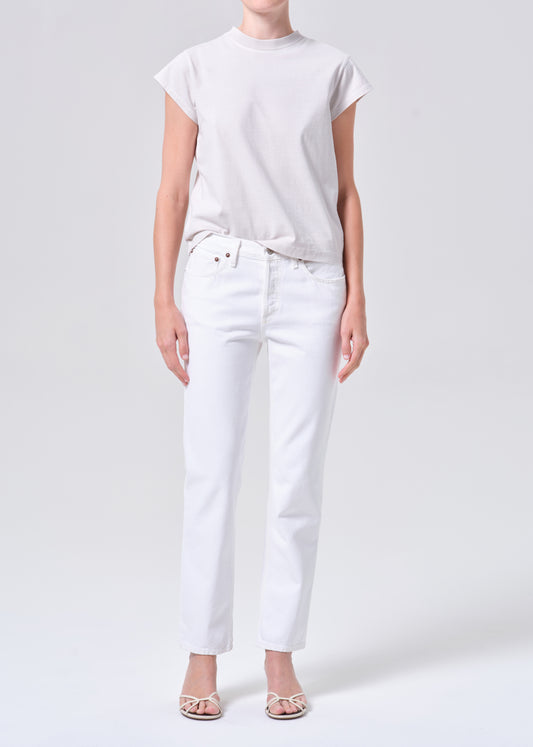 Person wearing a plain white t-shirt and white pants on a light gray background