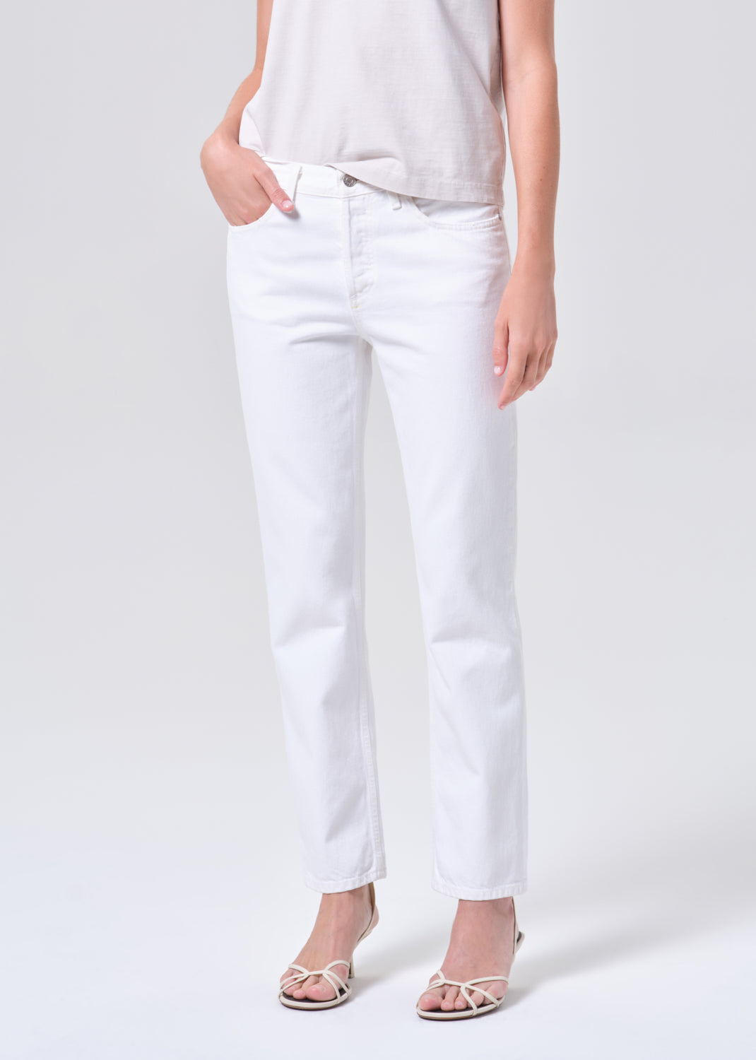 Person wearing white jeans on a plain background