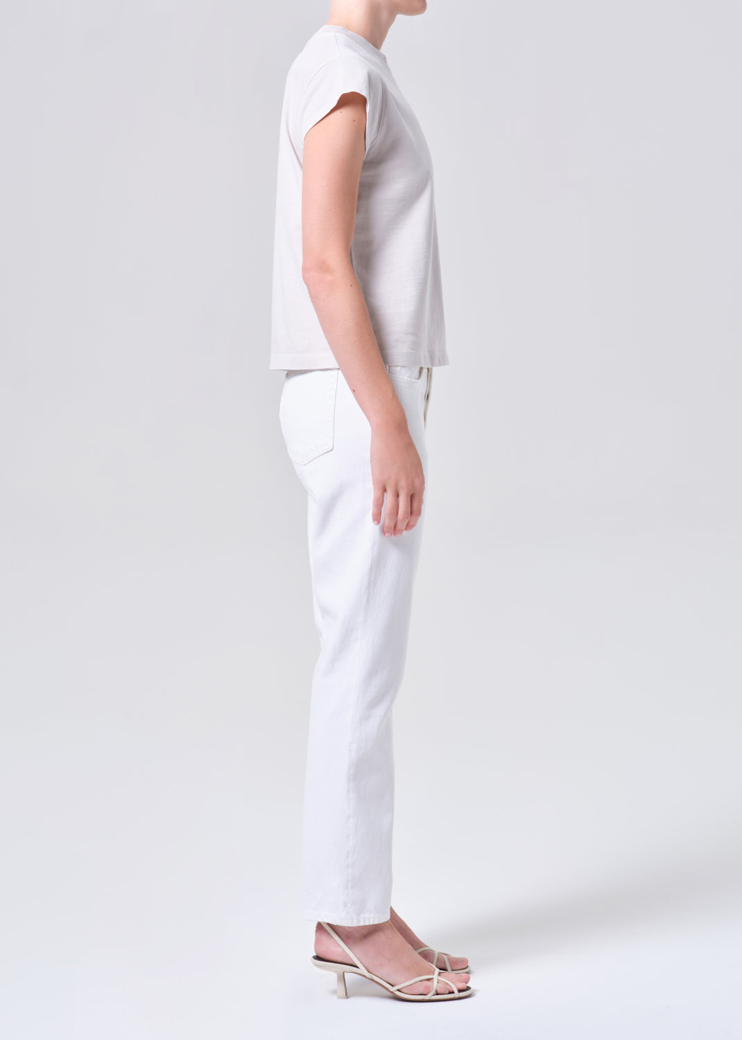 Person wearing a plain white t-shirt and pants on a light gray background