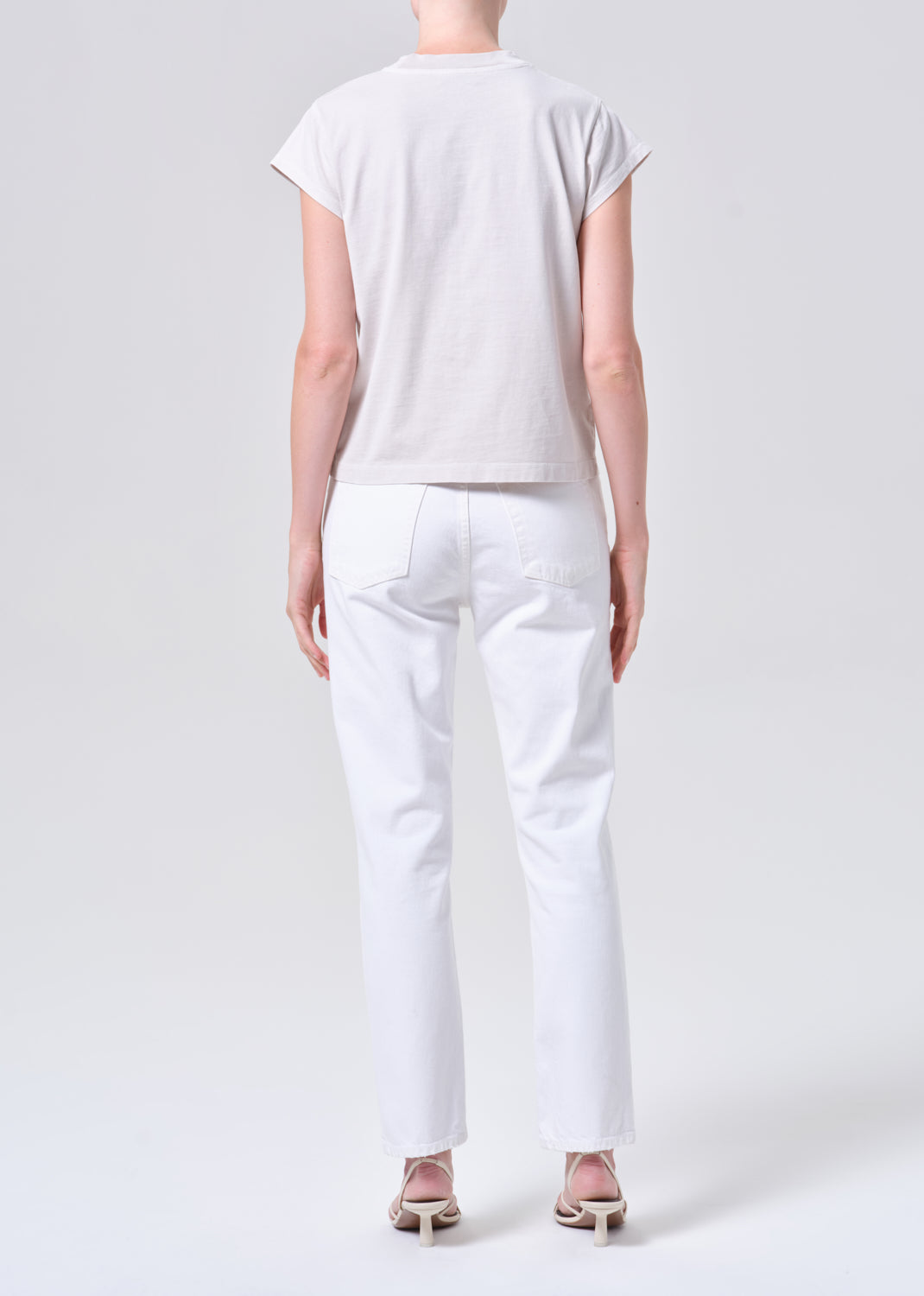 Person wearing a white t-shirt and pants on a plain background