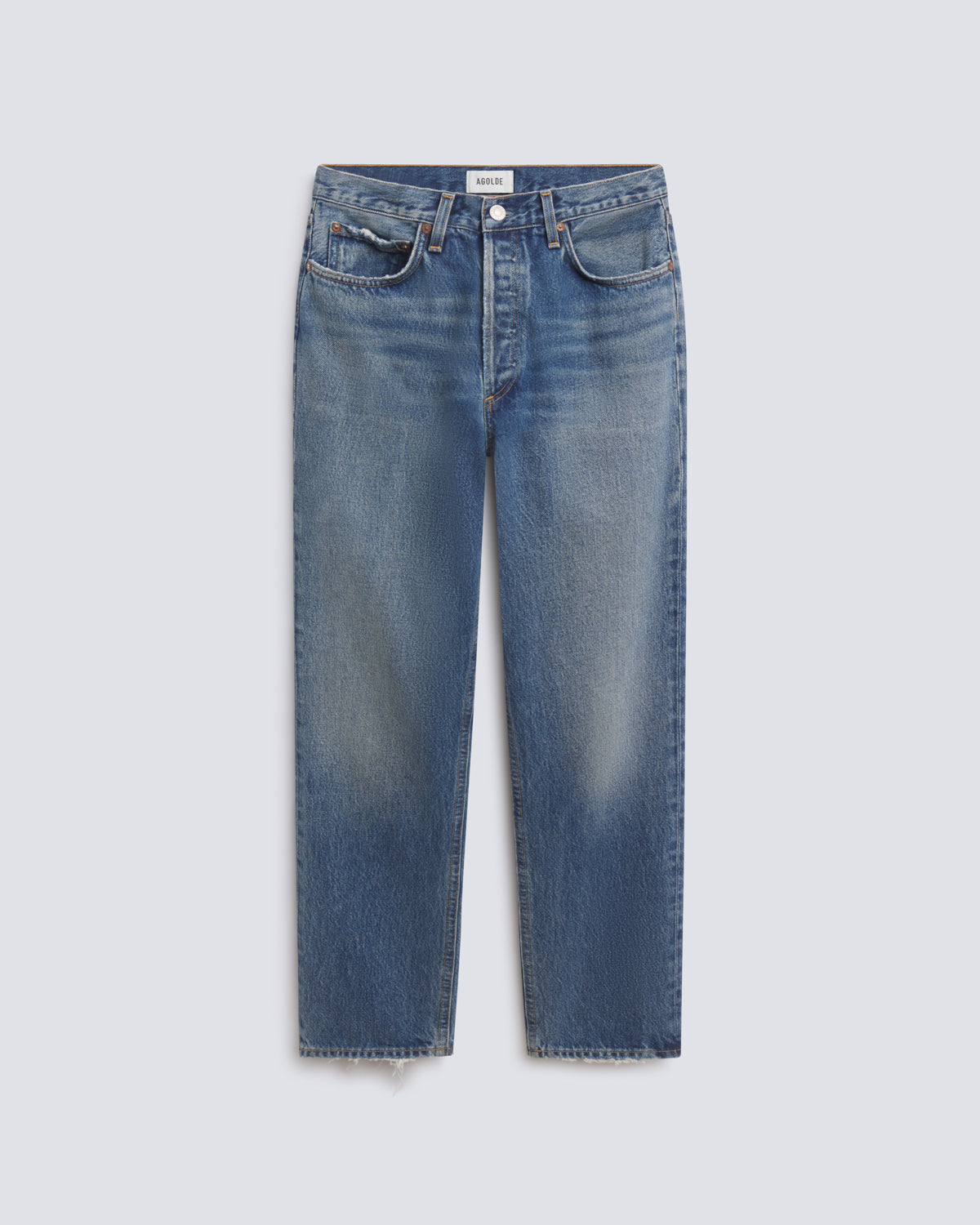 Flat lay of blue denim jeans on a grey background.