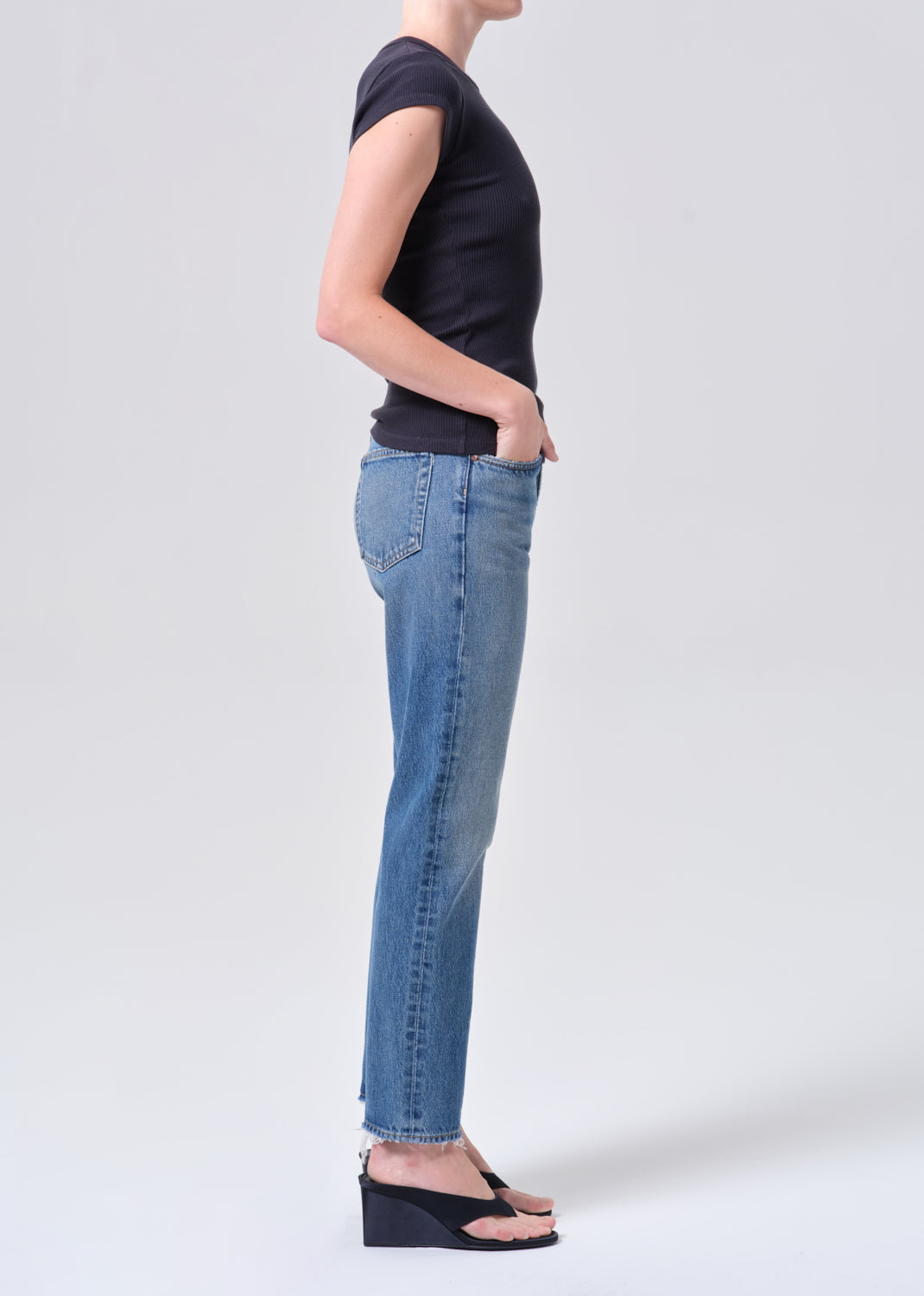 Person wearing a black t-shirt and blue jeans on a white background