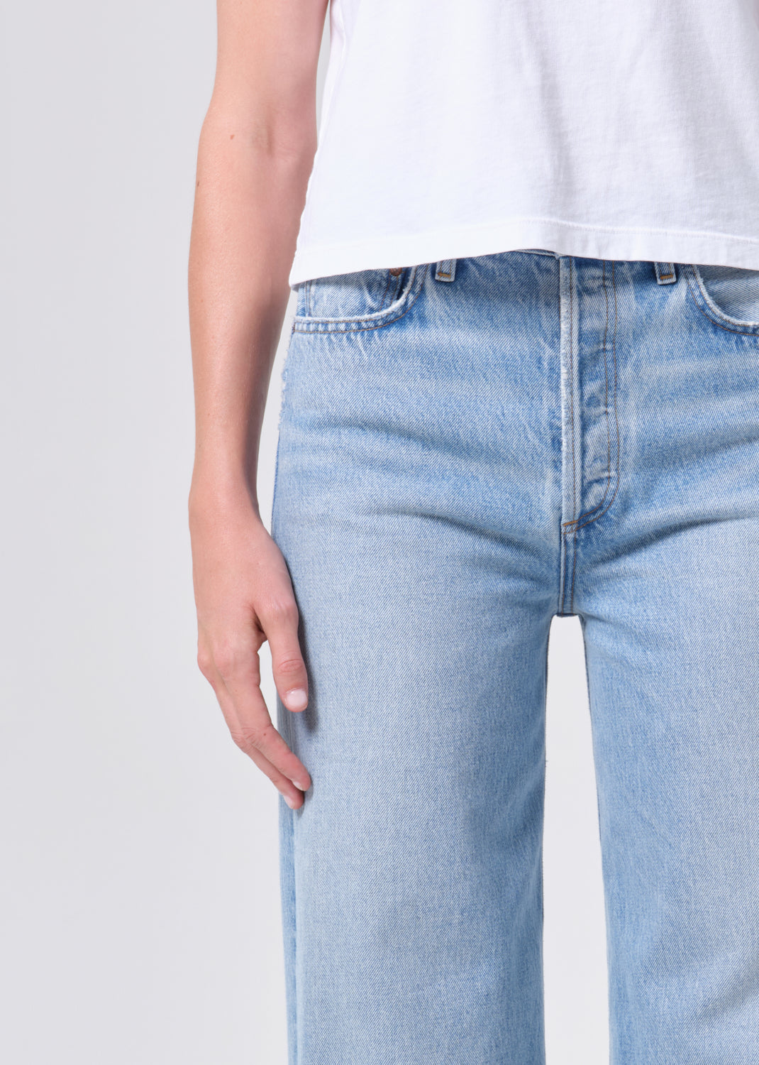 Light blue jeans worn by a person on a plain background