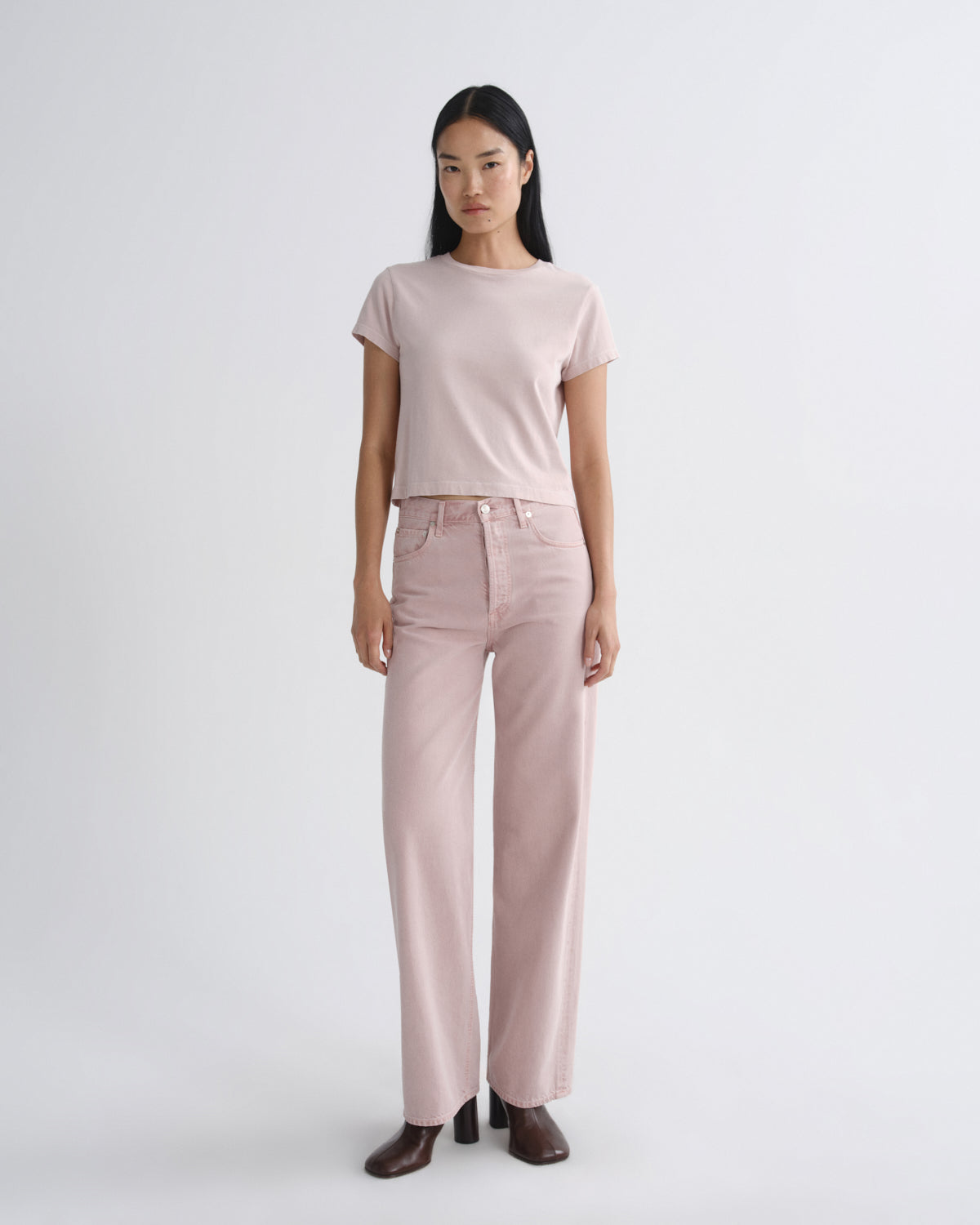 Woman wearing a light pink t-shirt and pants on a white background