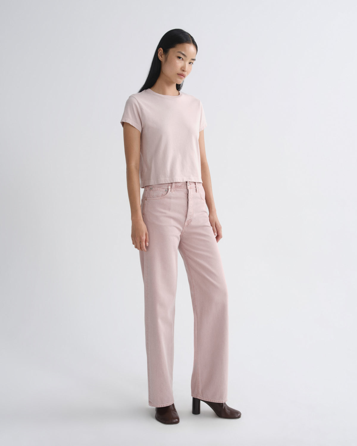 Woman wearing a light pink top and pants on a white background