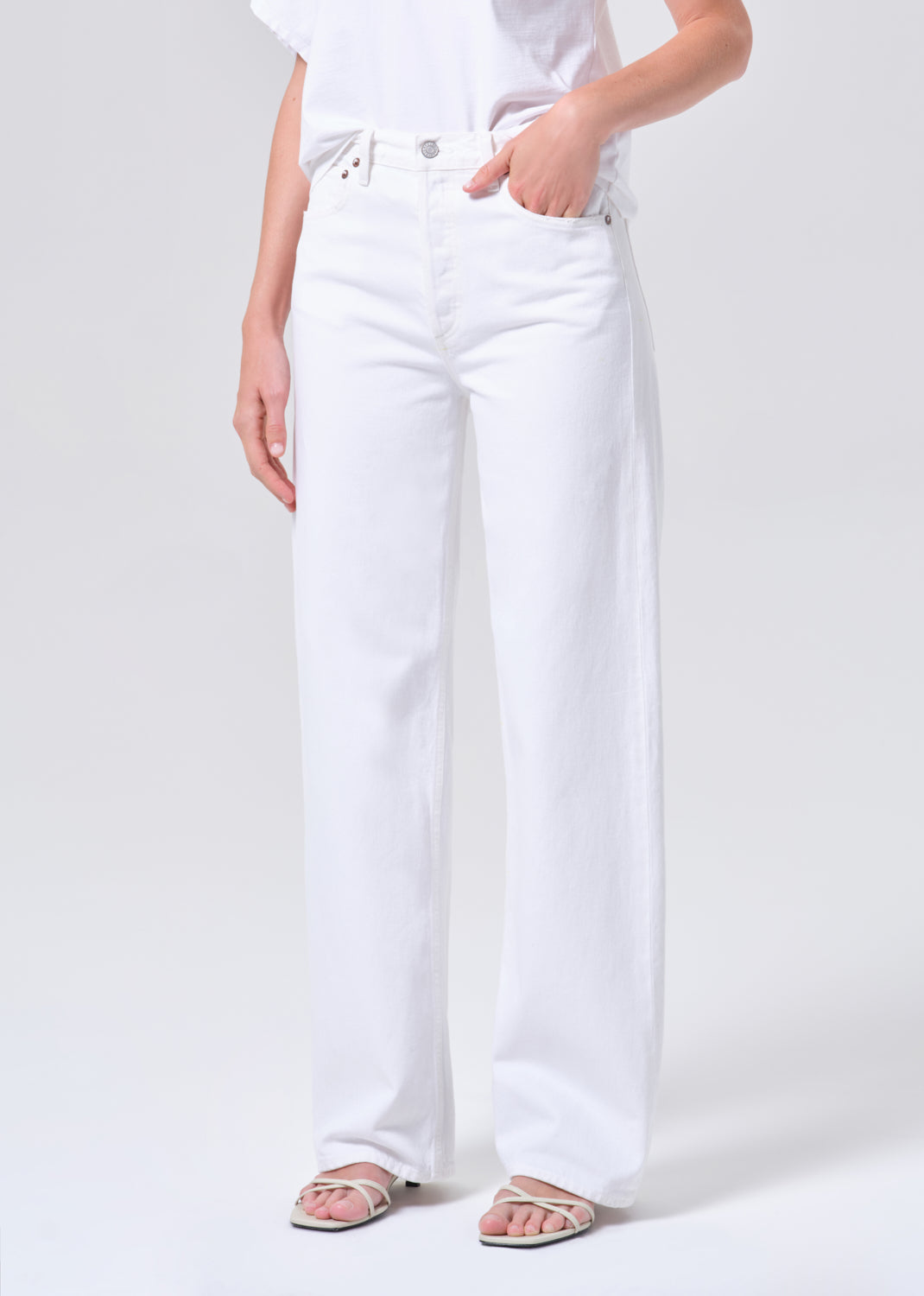 Person wearing white jeans on a plain background