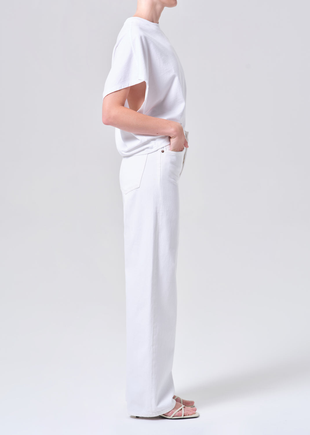 Person wearing a plain white t-shirt and pants on a light gray background