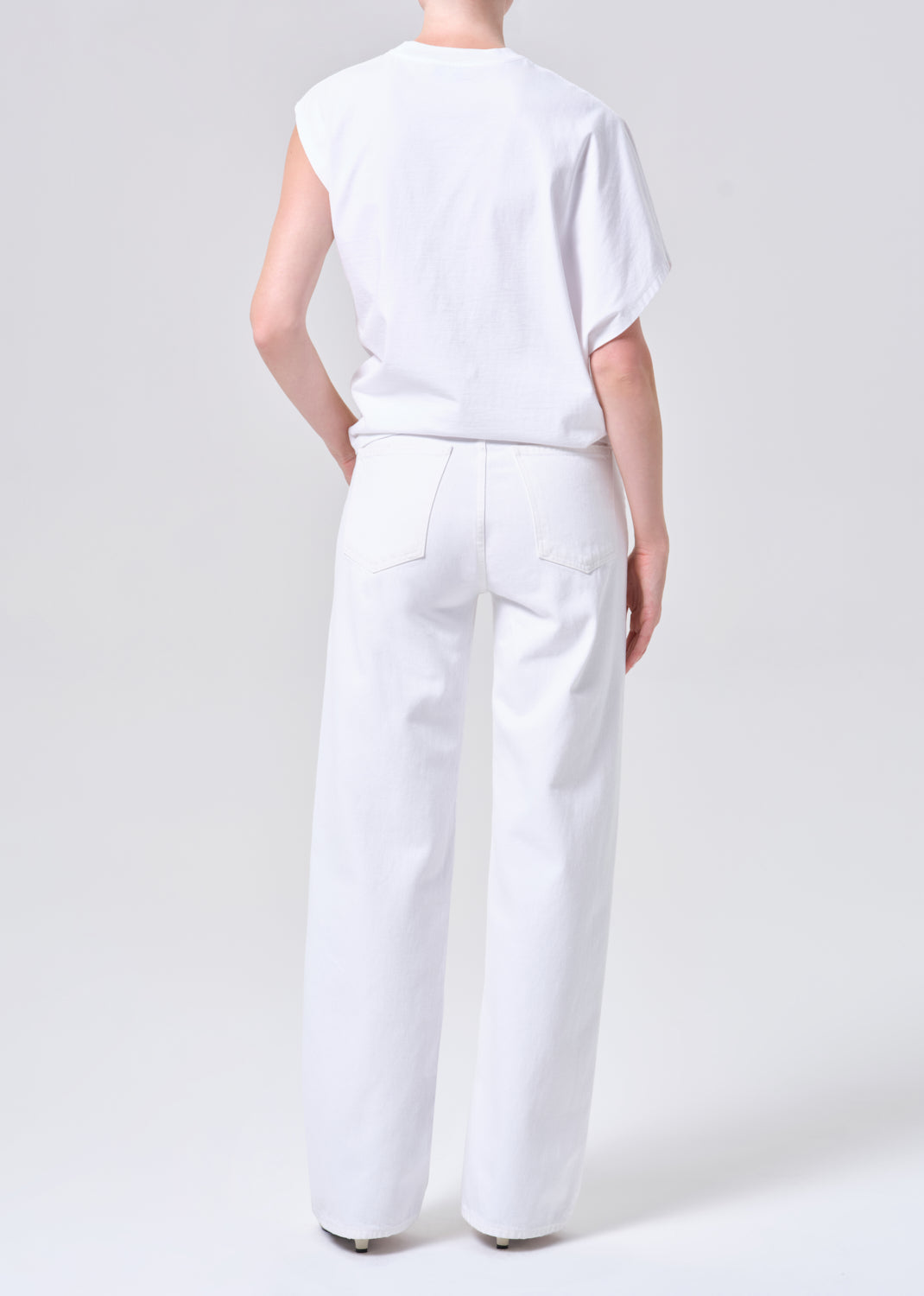 Person wearing a white sleeveless top and wide-leg pants on a plain background