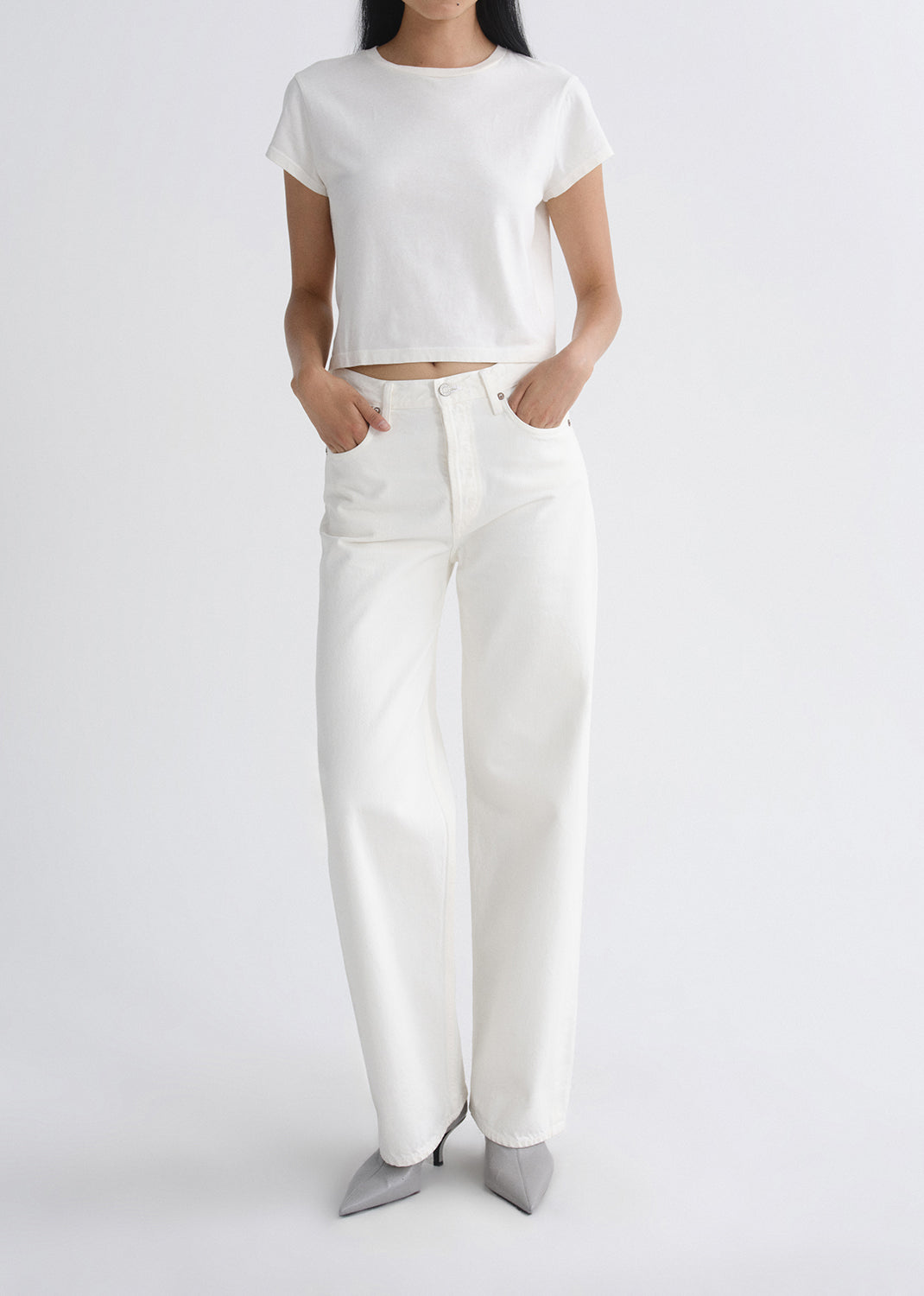 Person wearing a white outfit with wide-leg pants on a grey background