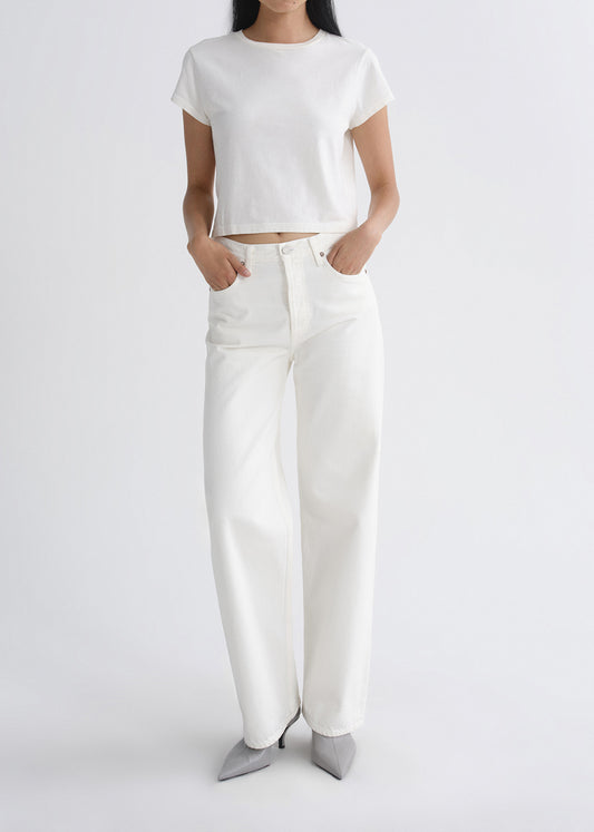 Person wearing a white outfit with wide-leg pants on a grey background