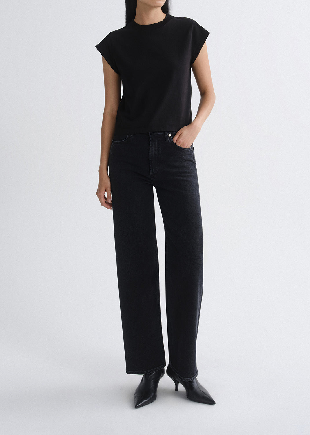 Person wearing a black sleeveless top and black pants on a grey background