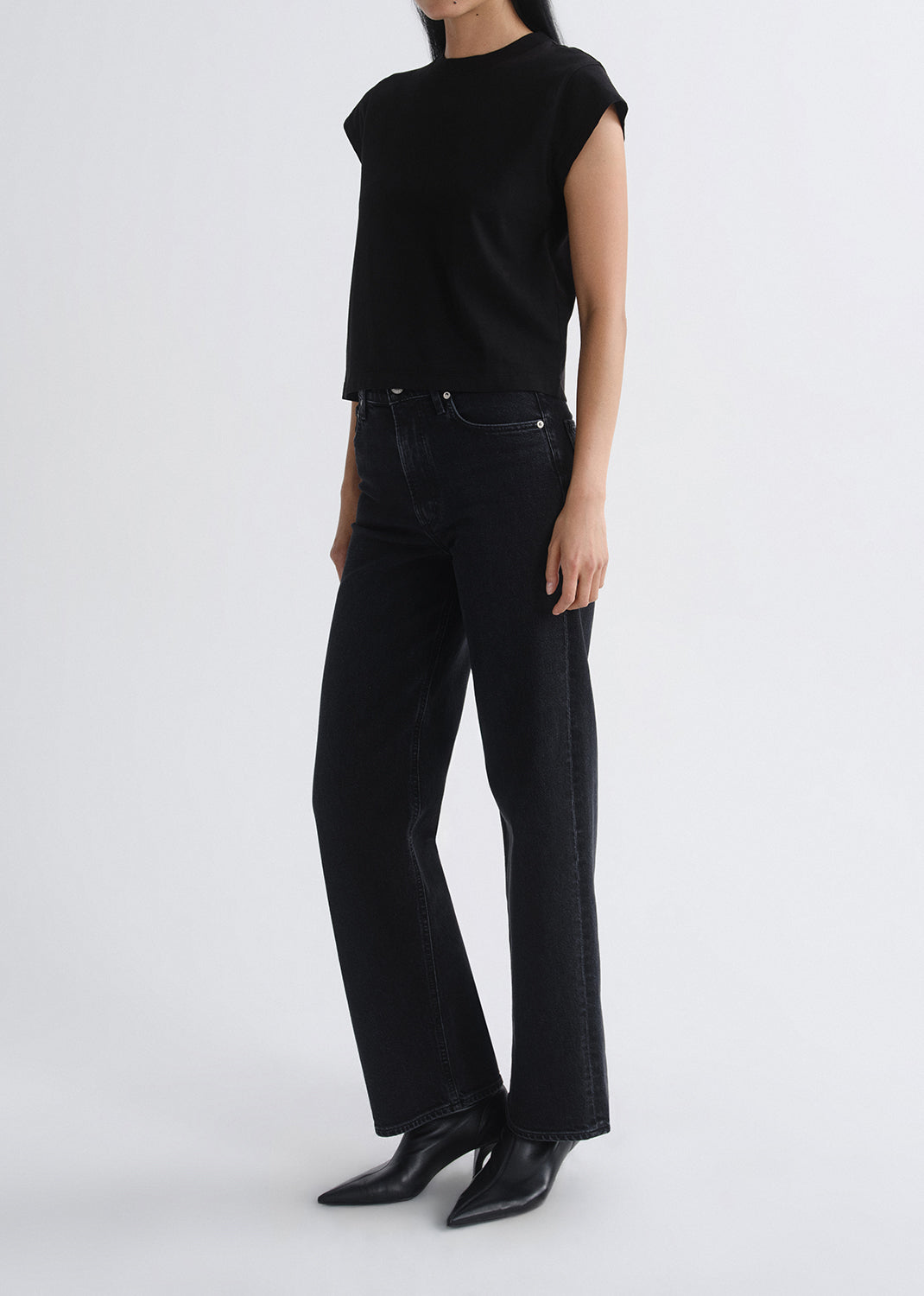 Person wearing a black sleeveless top and black pants on a grey background