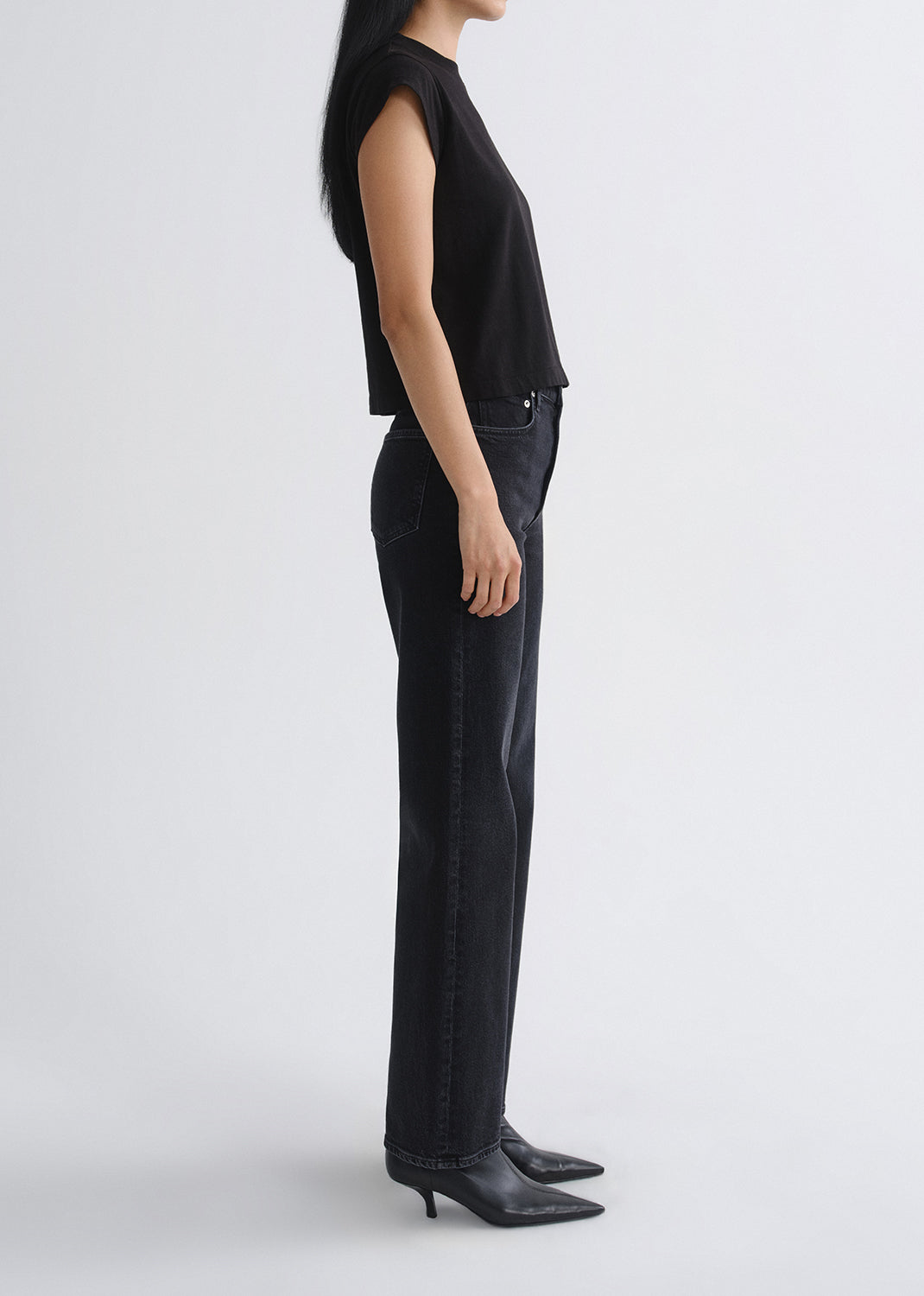 Person wearing a black sleeveless top and black pants on a grey background