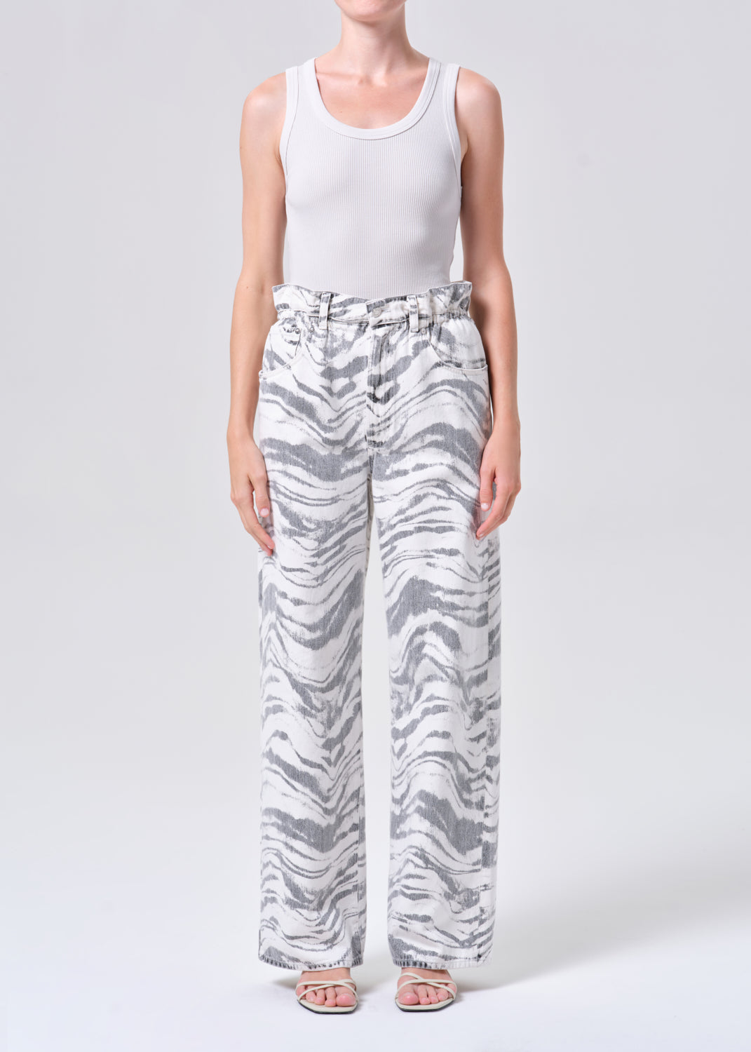 Person wearing a white tank top and zebra-striped pants on a white background