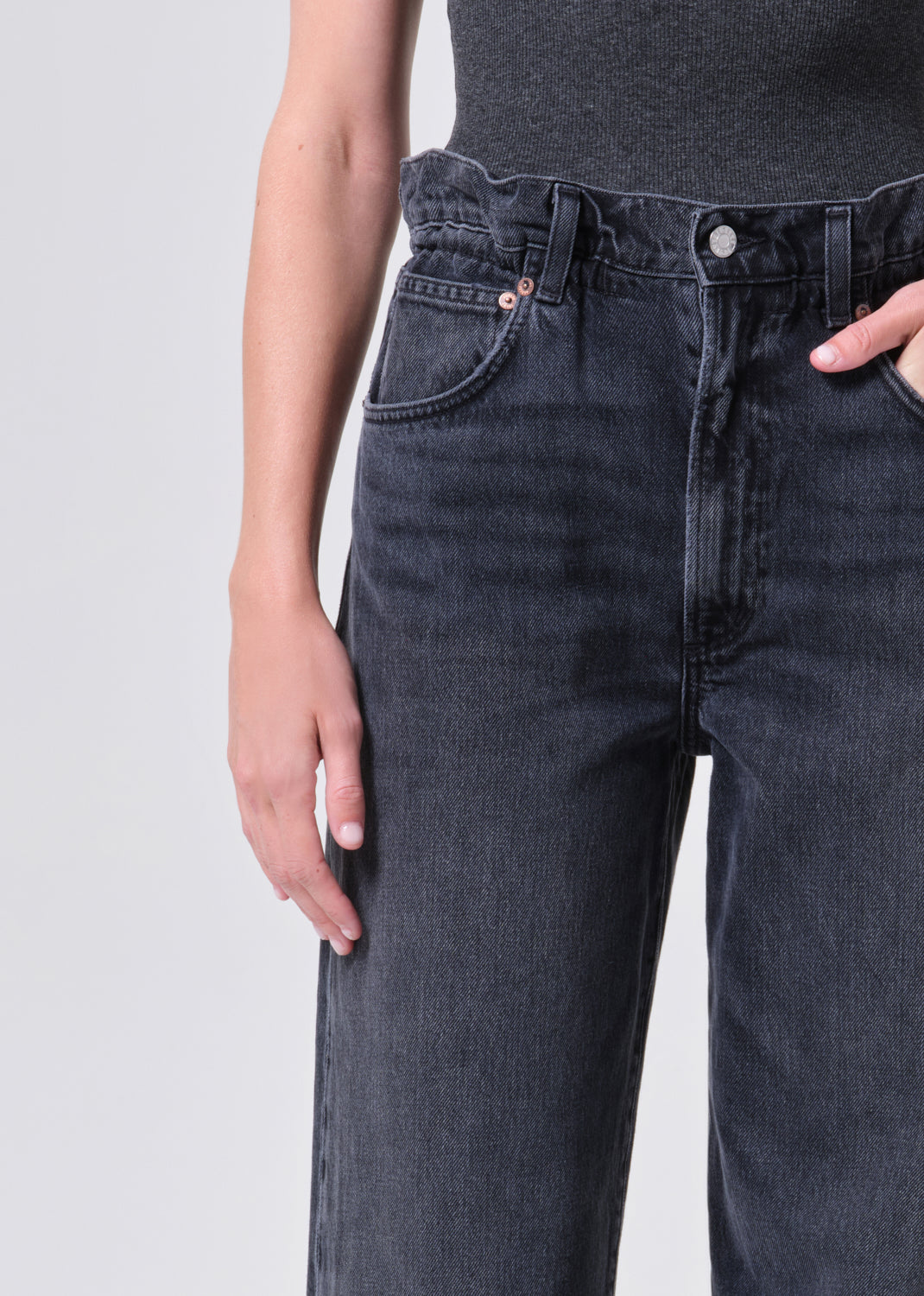 Person wearing dark blue jeans on a plain background