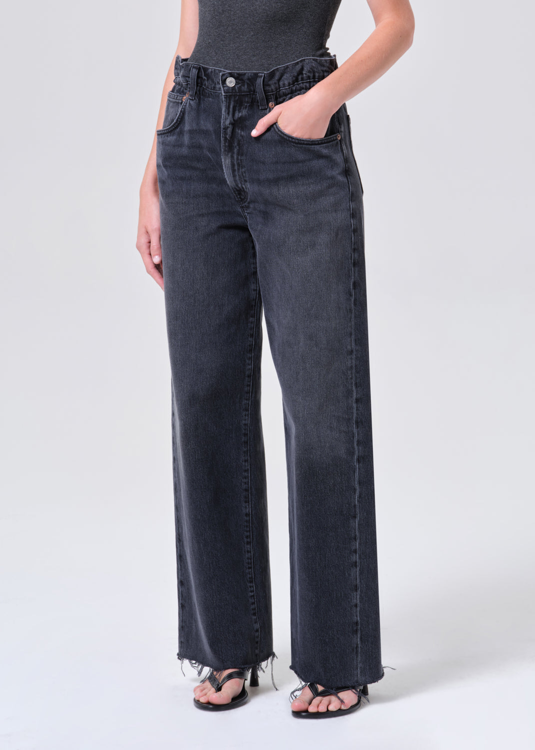 Person wearing black high-waisted jeans on a white background
