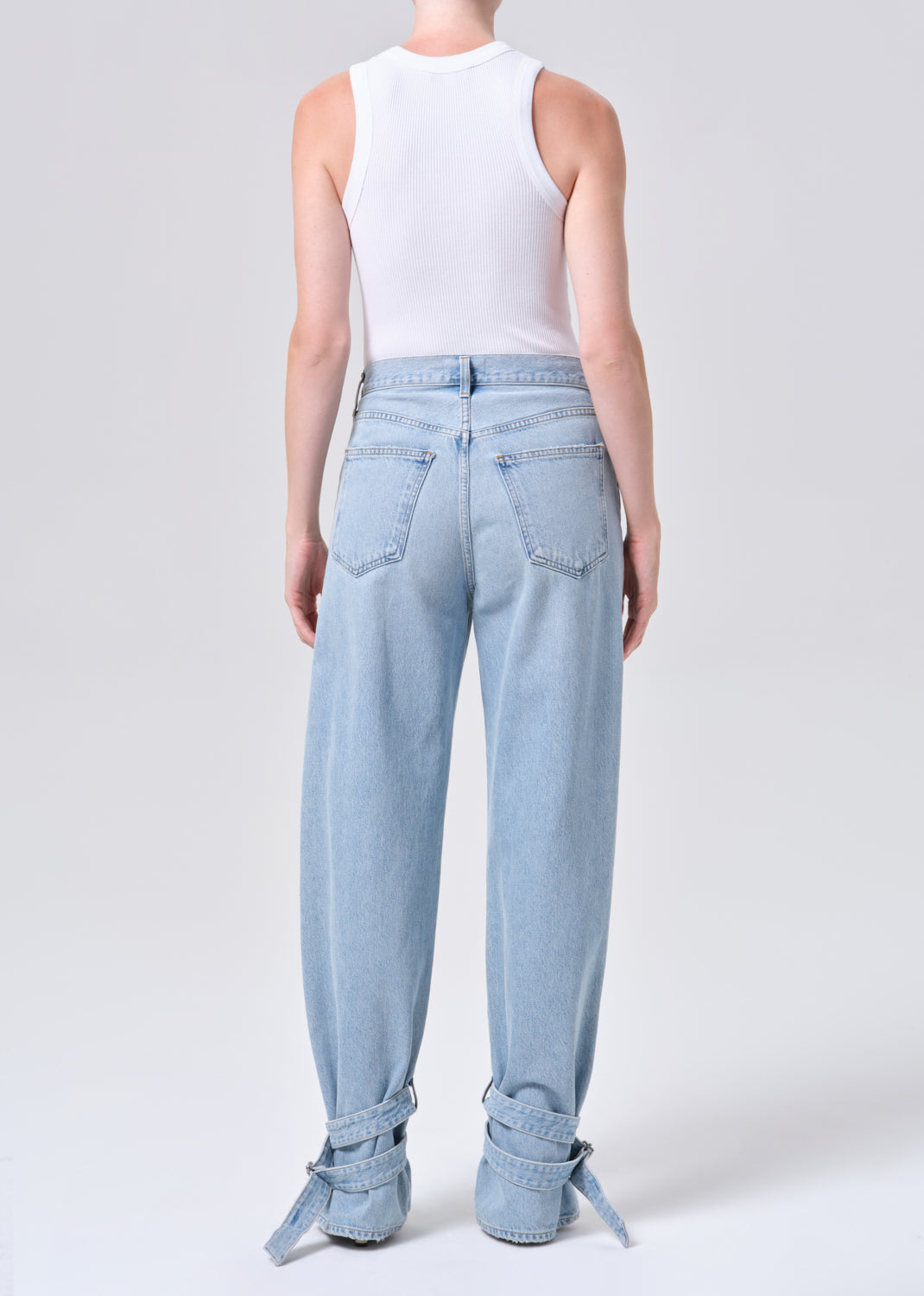 Light blue jeans with rolled-up cuffs worn by a person on a white background