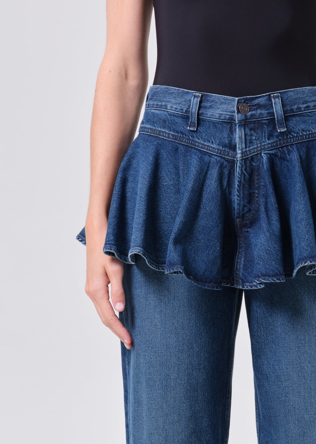 Blue denim peplum top worn by a person on a plain background