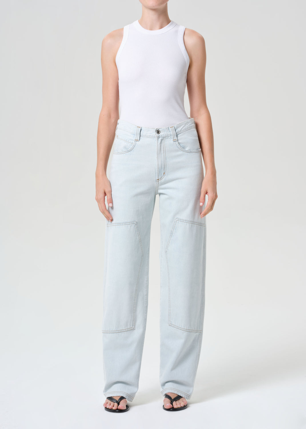 Person wearing light blue jeans and a white top on a white background