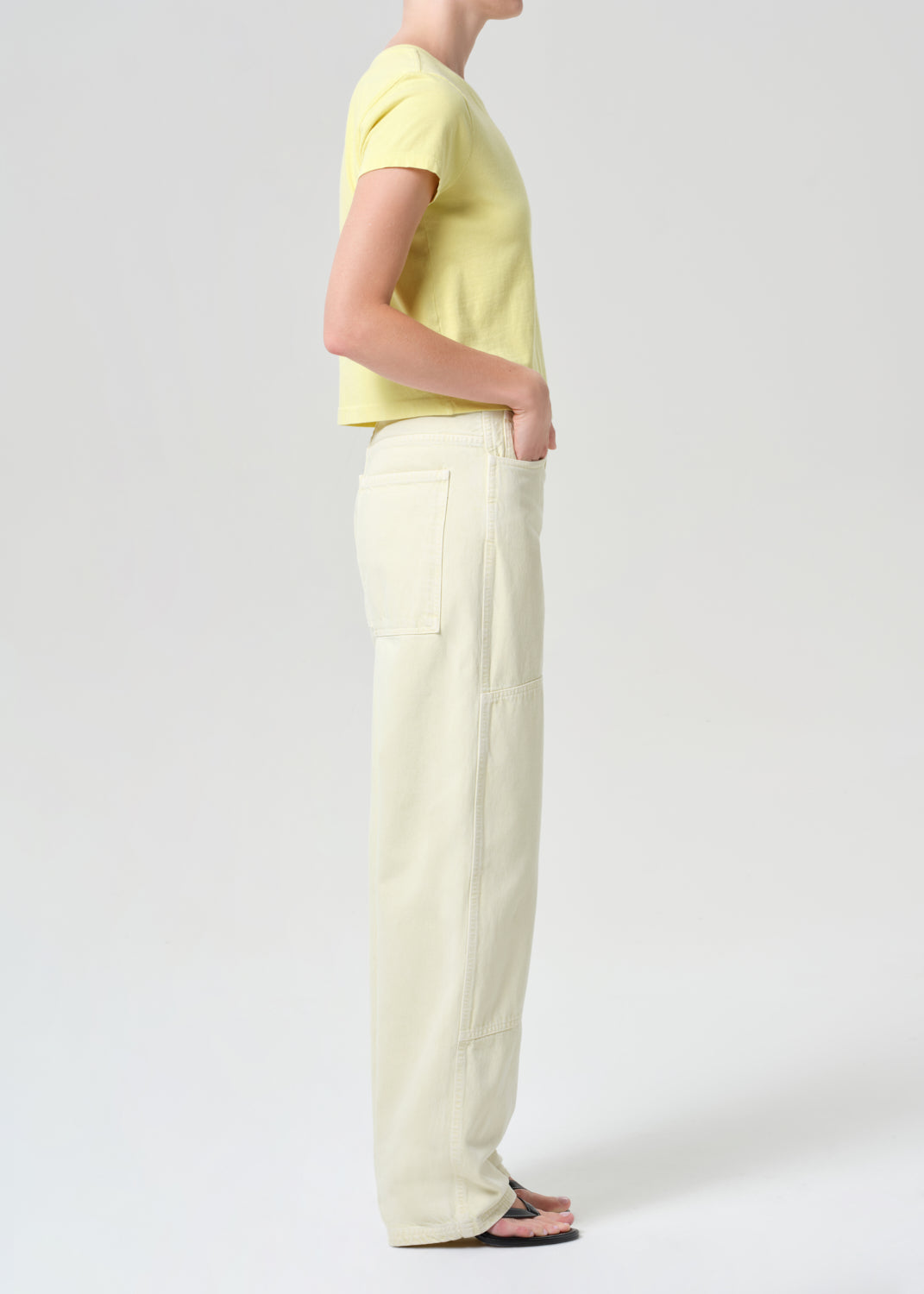 Person wearing a yellow top and white pants on a plain background