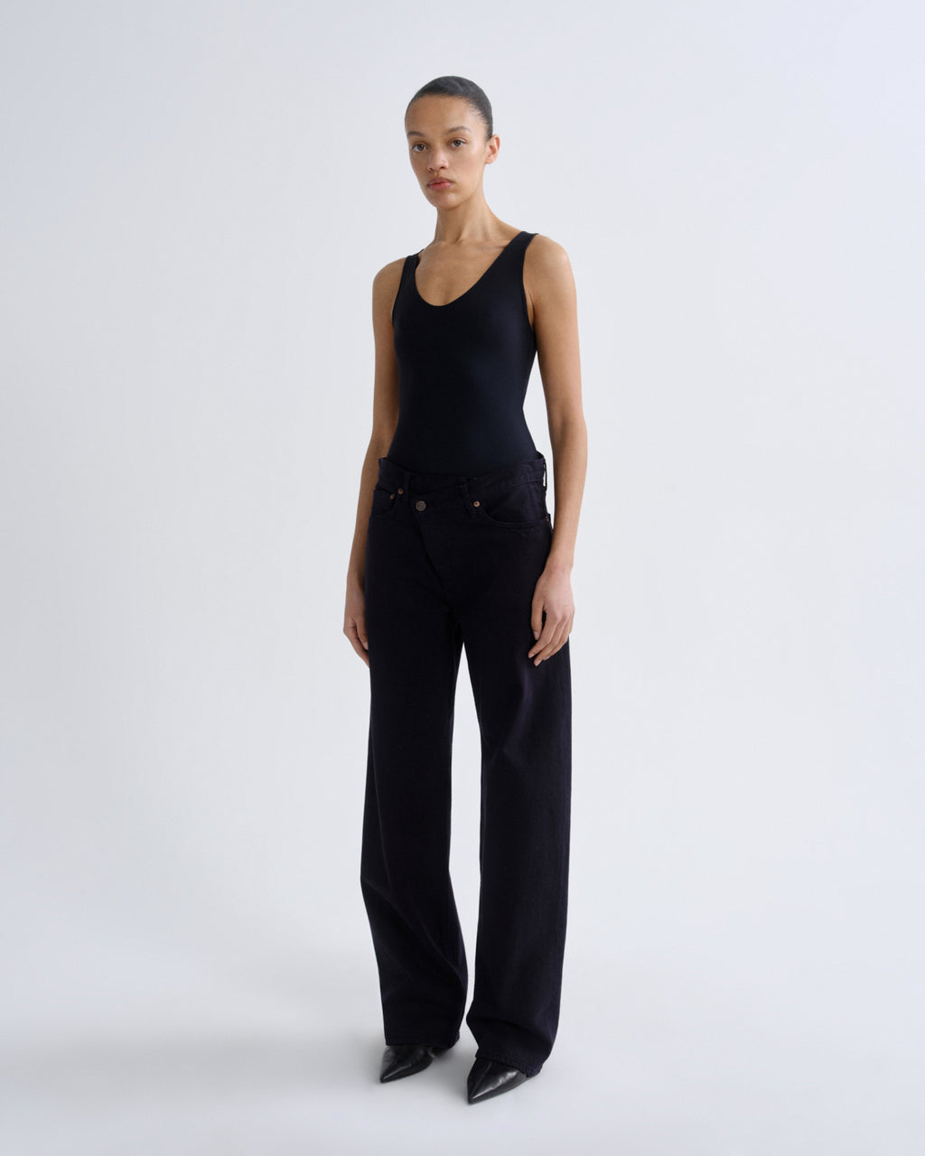 Person wearing a black sleeveless top and wide-leg pants on a grey background