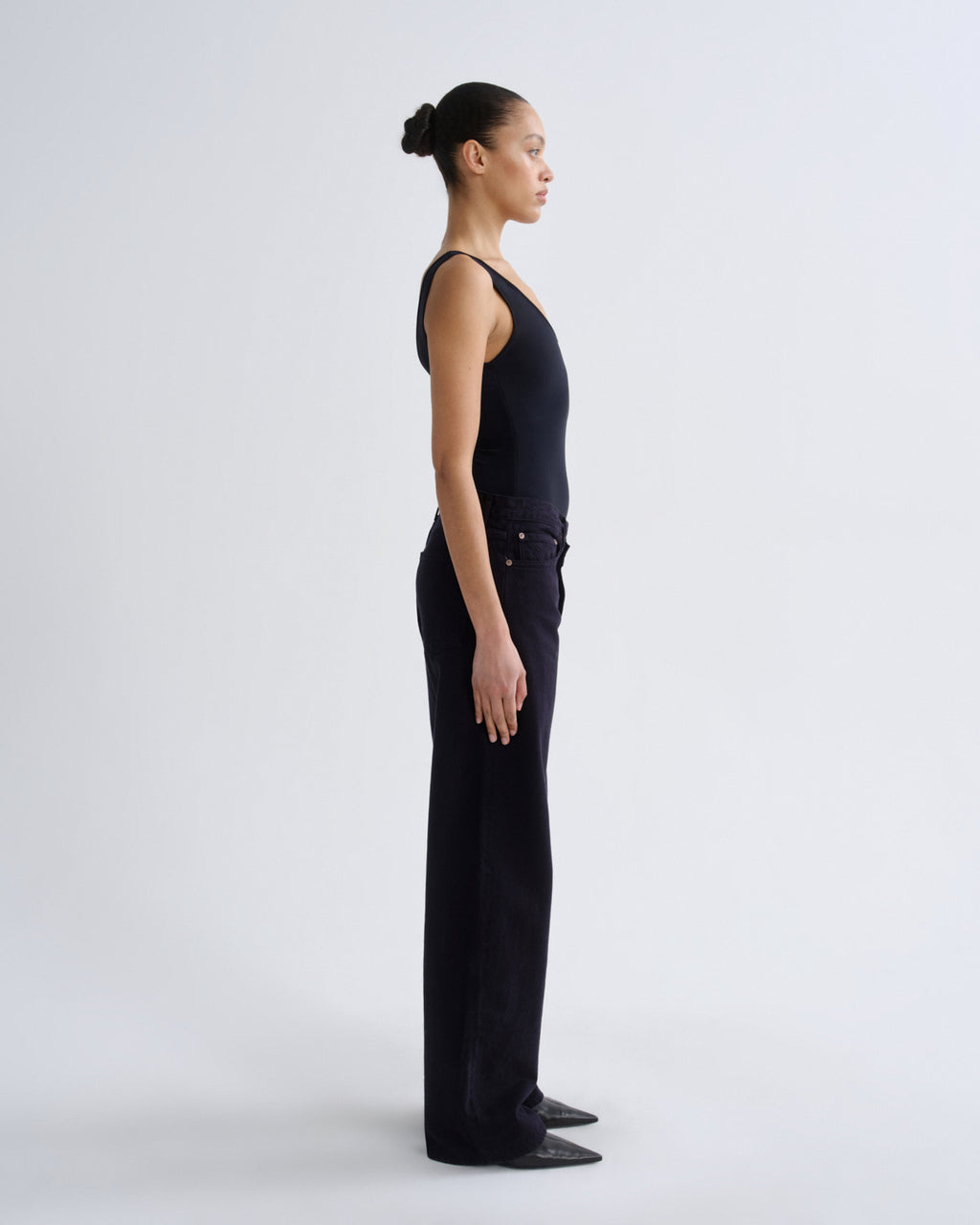 Person wearing a black sleeveless top and pants on a grey background
